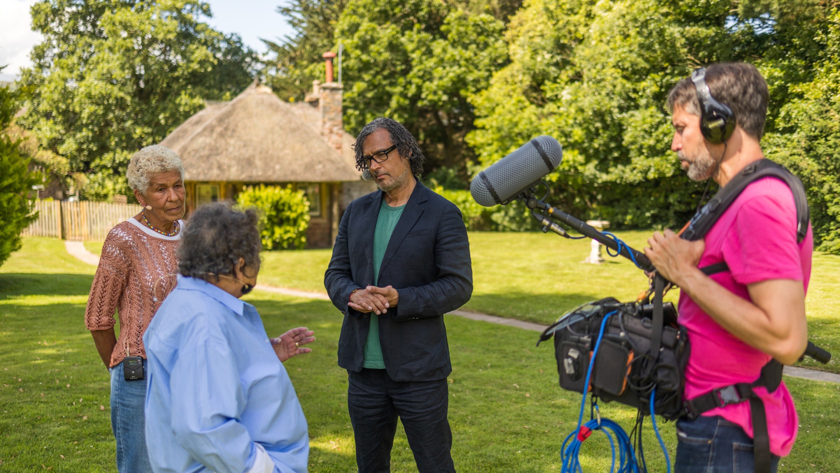 Two women are being interviewed by a historian and recorded for a podcast episode, they stand speaking together
