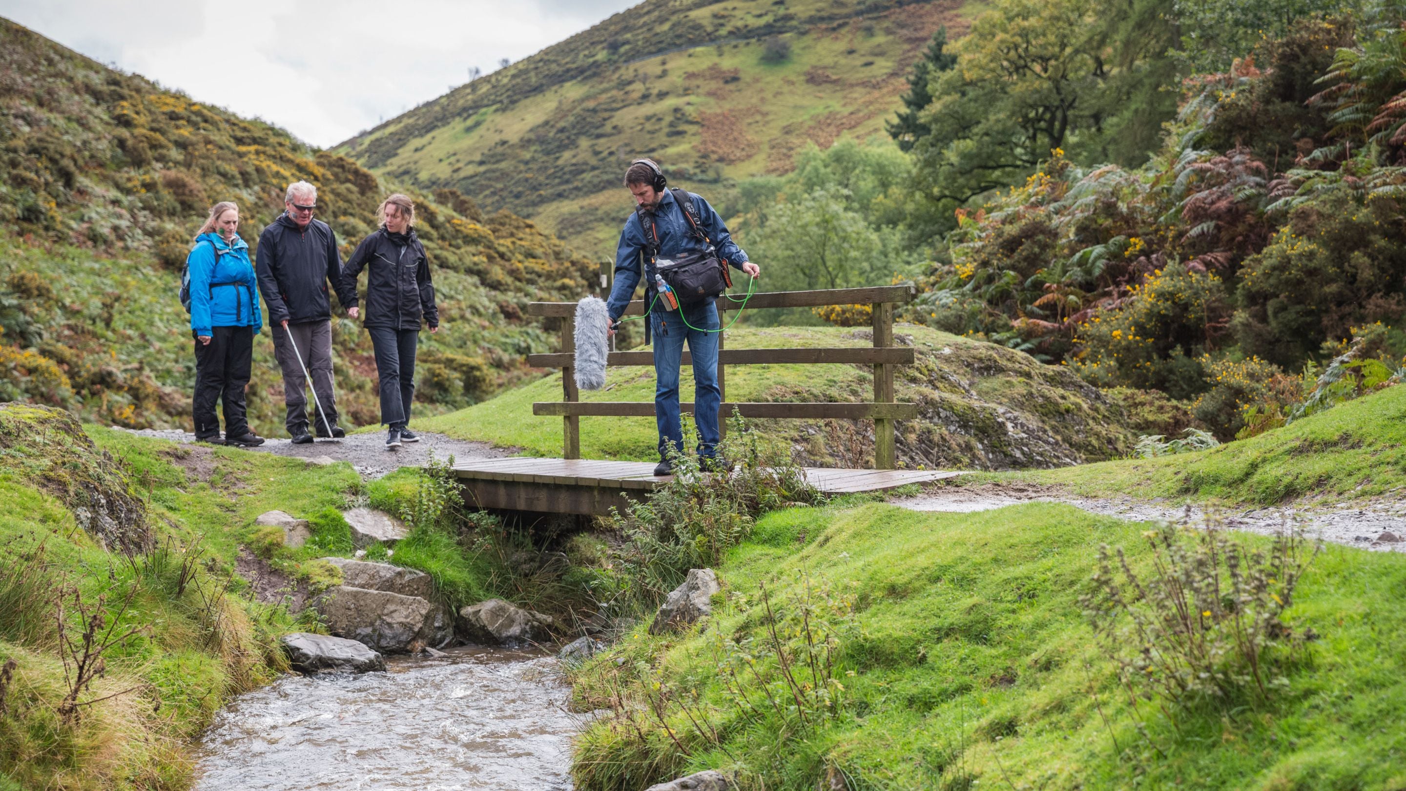 Four people walking along a path as part of a podcast recording at Carding Mill Valley, Shropshire