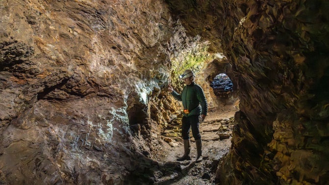 A man wearing a helmet and head torch inside an underground tunnel