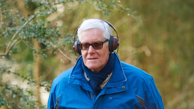 Visitor wearing headphones and walking in the grounds at Knightshayes, Devon