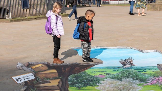Children standing on a blossom drawing on the pavement at St Phillip's Cathedral Square, Birmingham