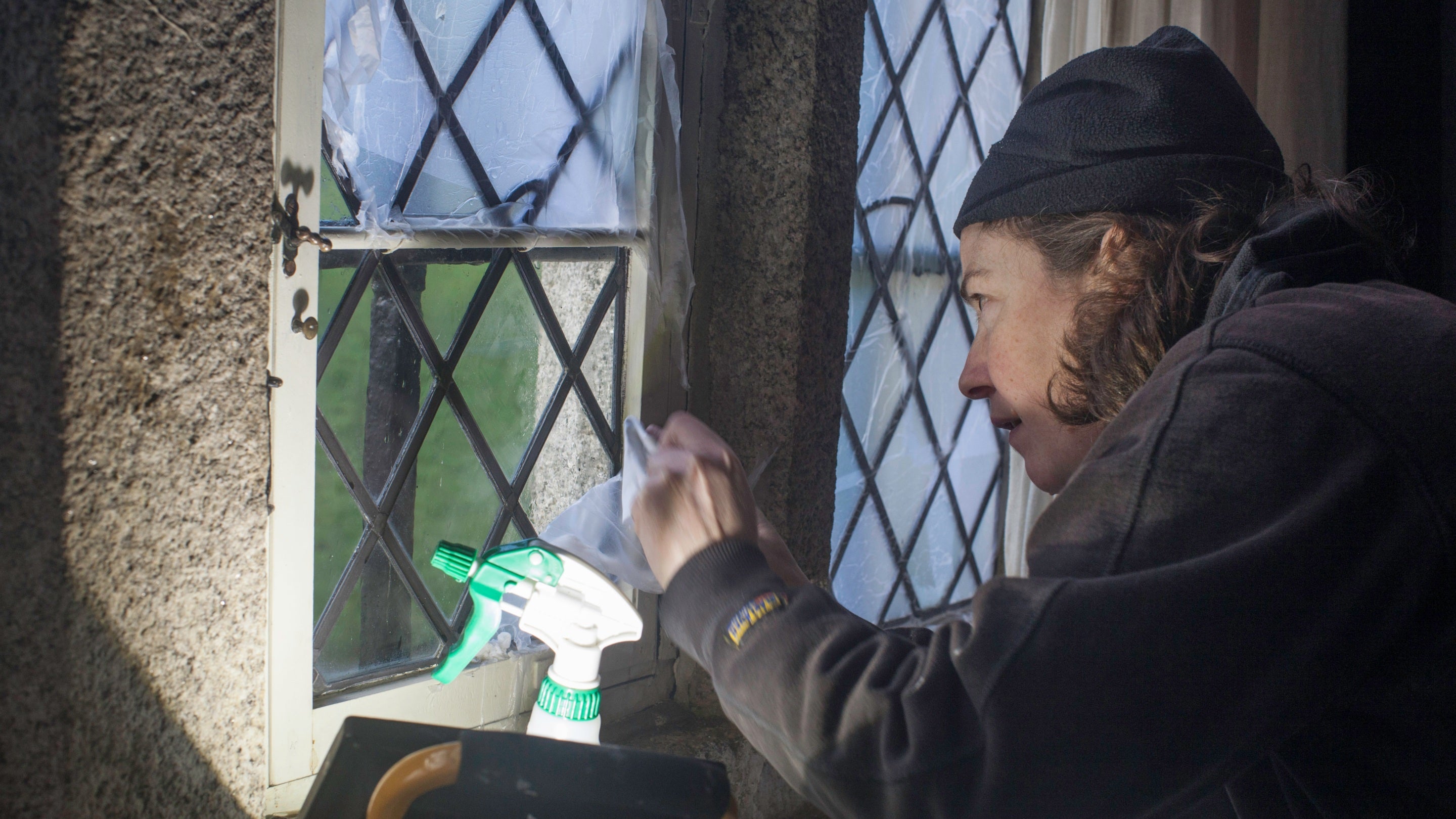 A man peeling film off a leaded window pane