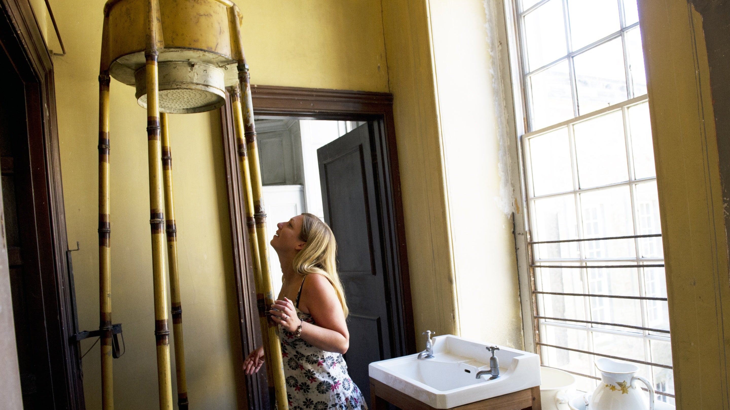Visitor looking at a nineteenth century shower at Calke Abbey, Derbyshire