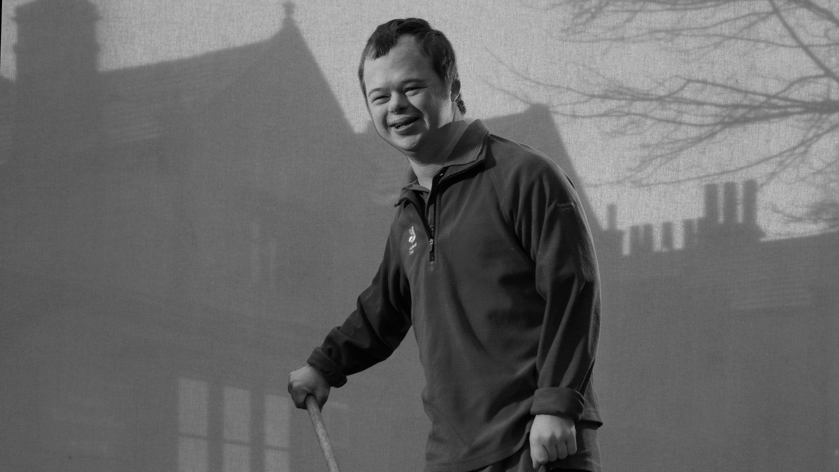 A black and white portrait of volunteer James Drury in front of a project of the house at Longshaw