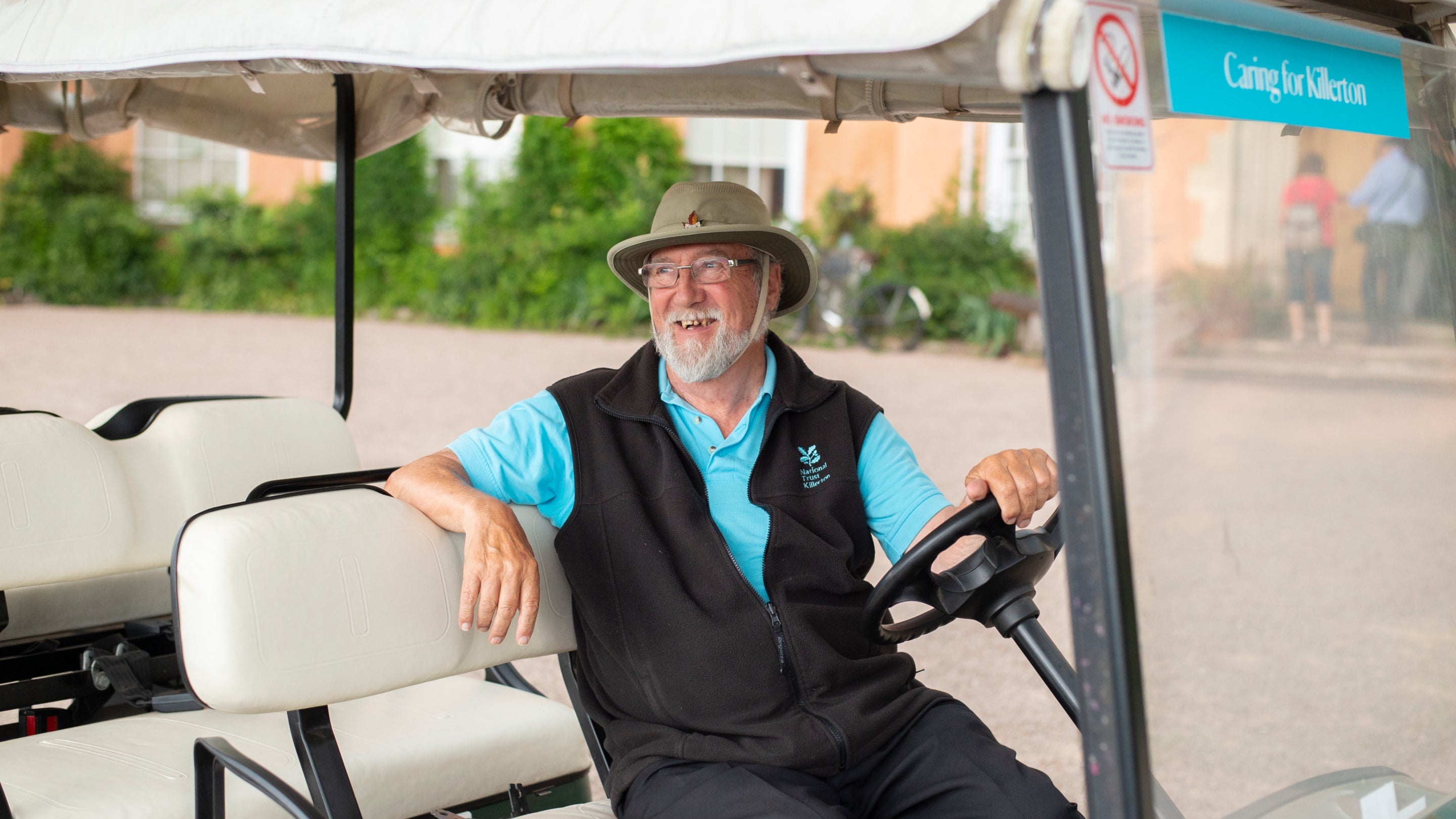 A volunteer in the driver's seat of a National Trust buggy at Killerton Devon