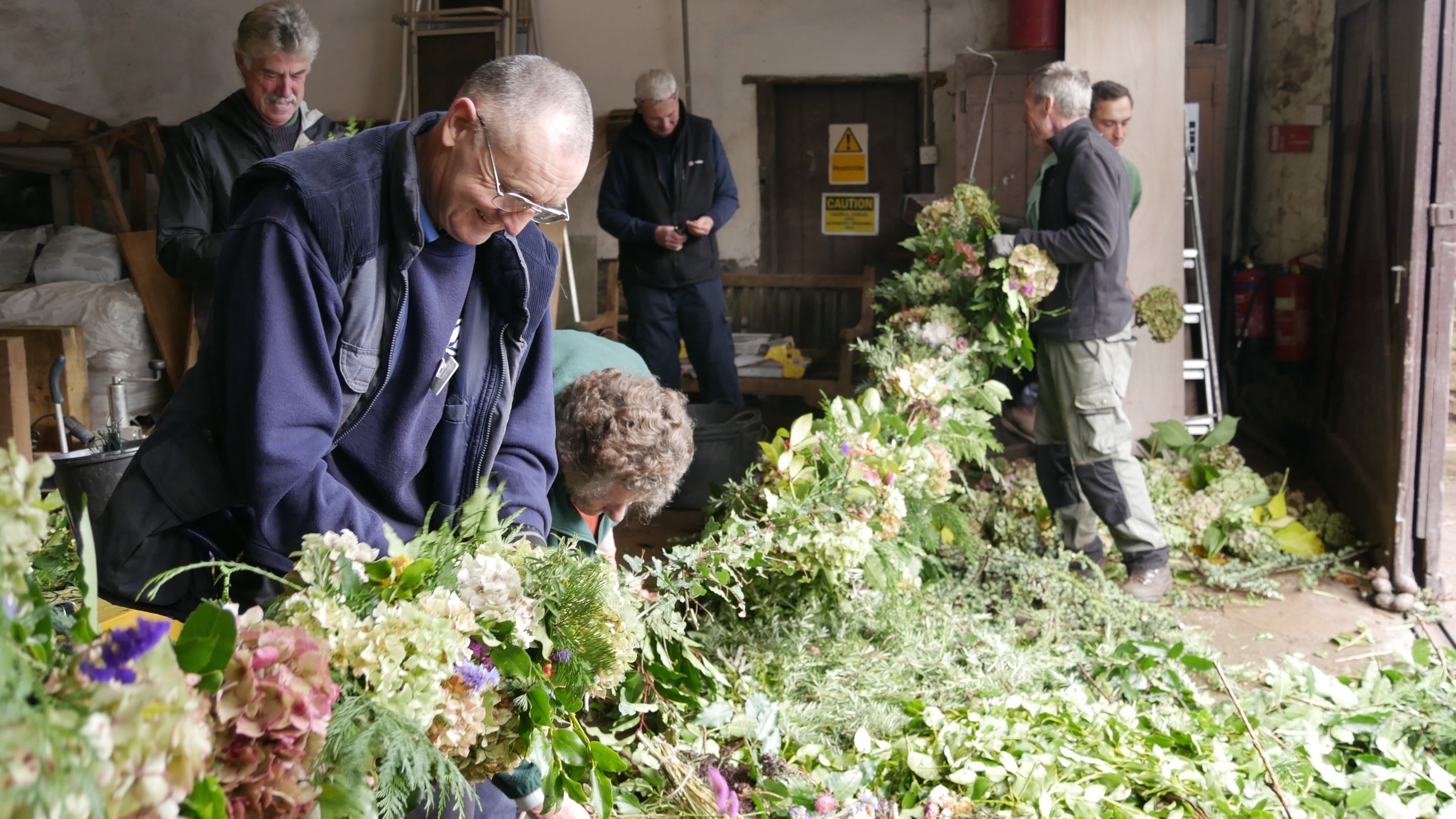 Garden staff and volunteers making a garland at Dunster Castle, Somerset