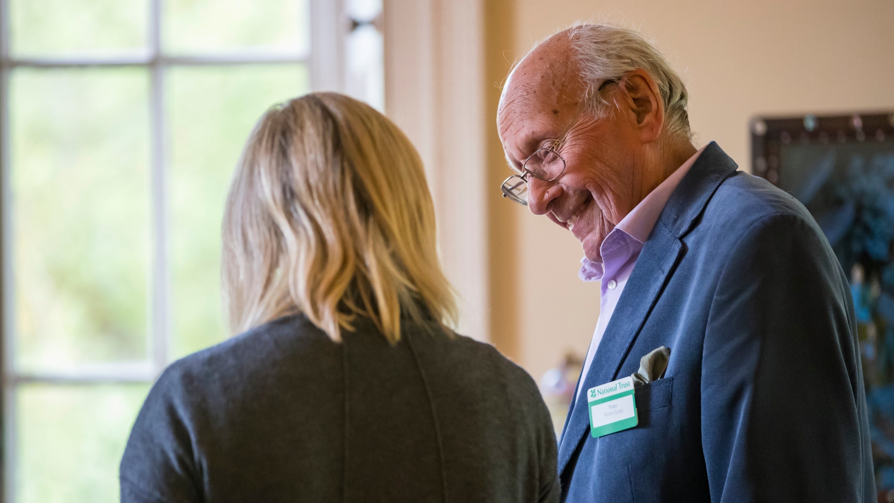 A volunteer room guide talks to a visitor at Greenway in Devon