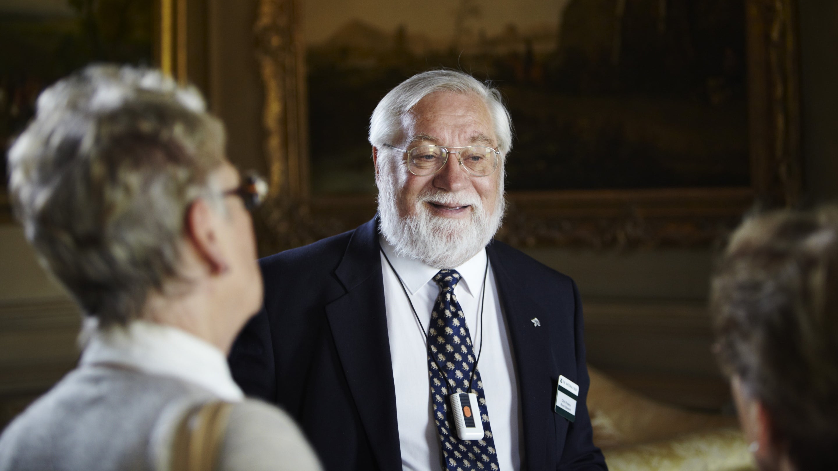 Visitors with a volunteer room steward at Petworth House, West Sussex