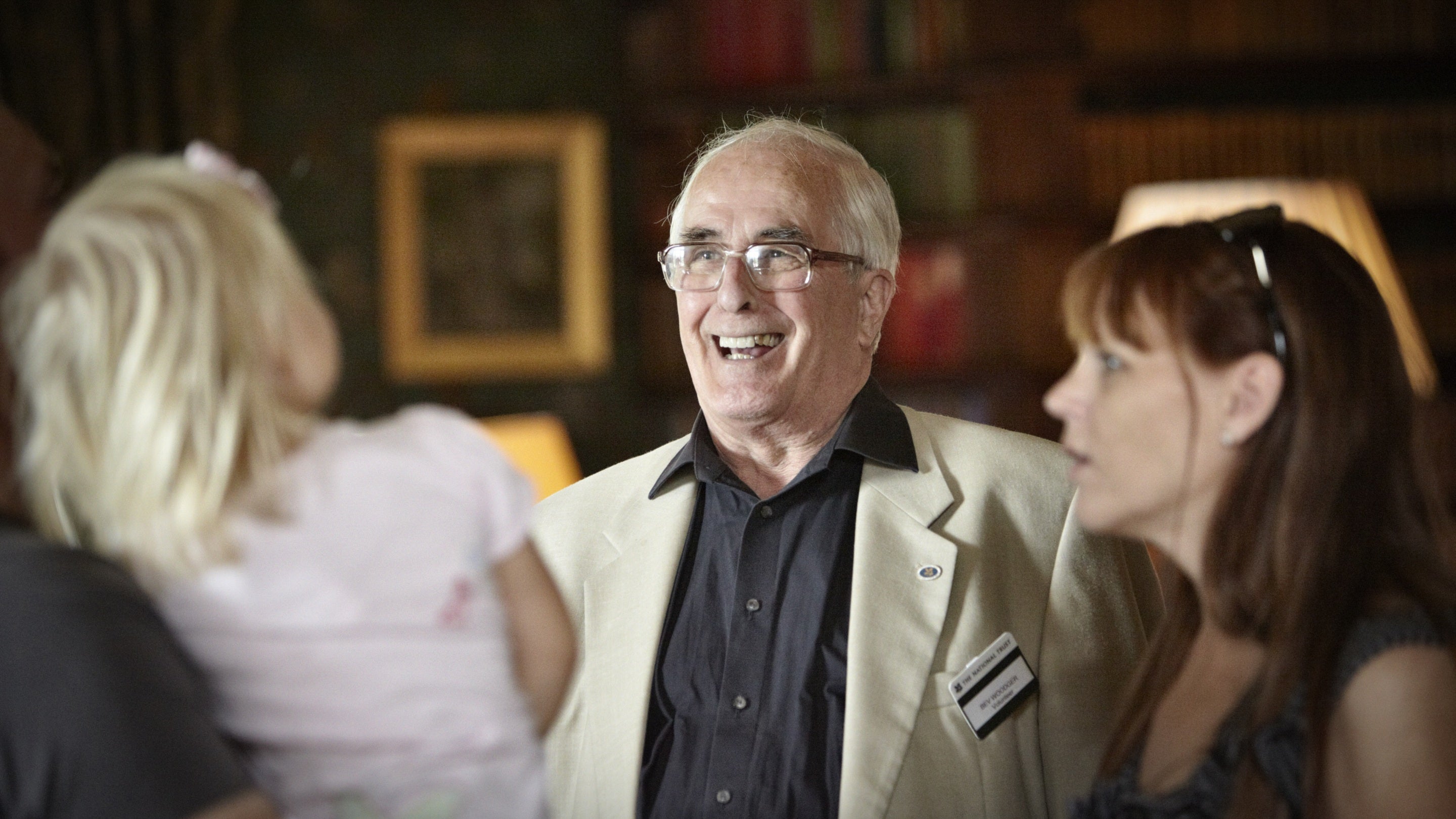 A volunteer talks to visitors in the library at Dunster Castle, Somerset