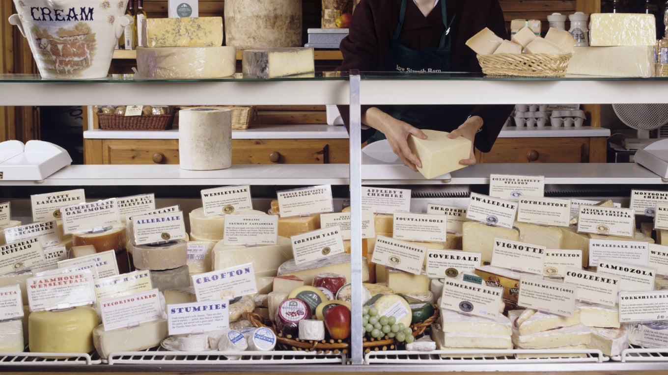 An array of cheeses on display behind a glass counter at Low Sizergh Barn farm shop in Kendal, Cumbria