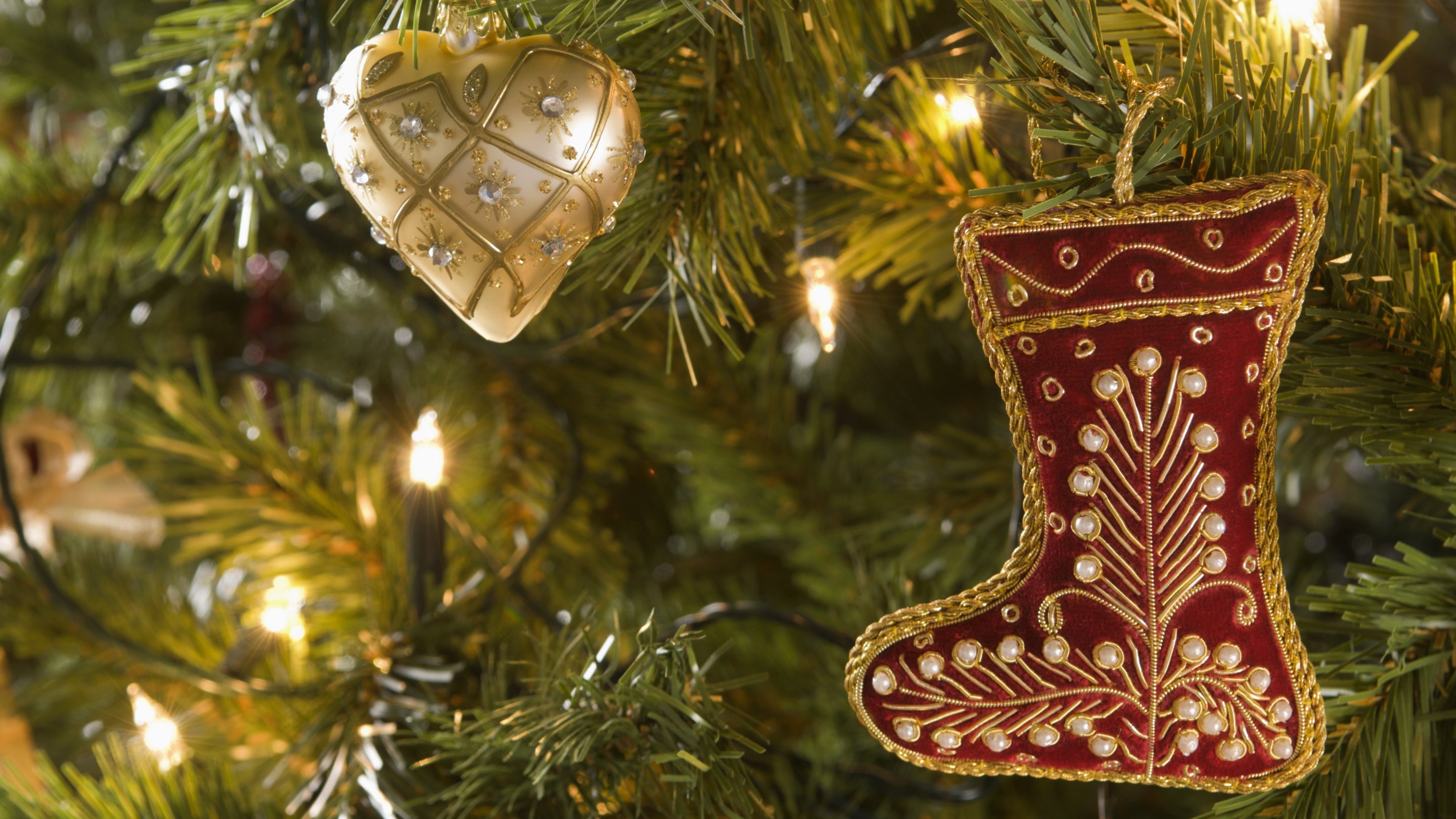 A gold heart and red stocking Christmas decoration in the branches of a Christmas tree