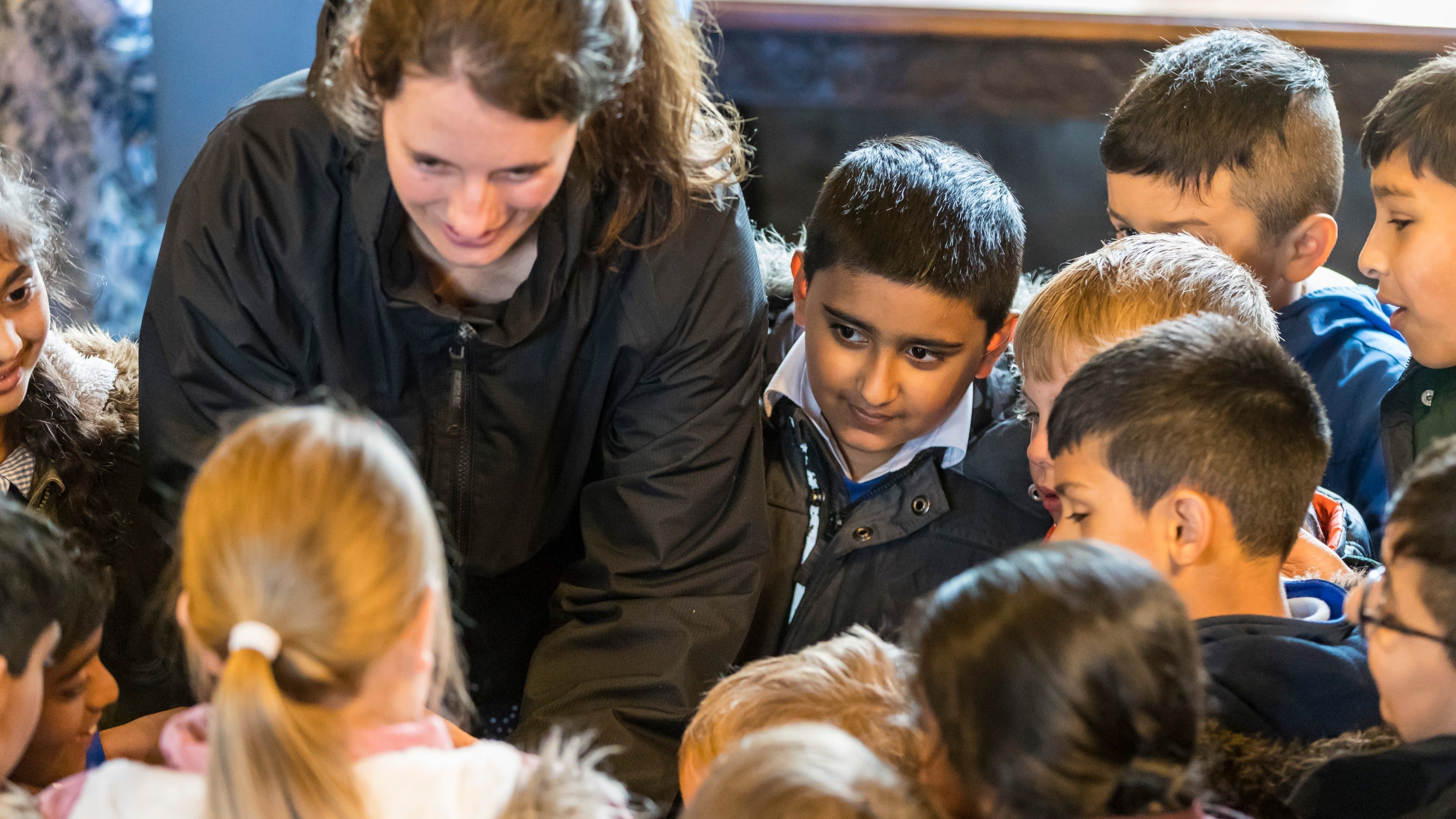 Close up of a group of children looking intently at something a guide is showing them