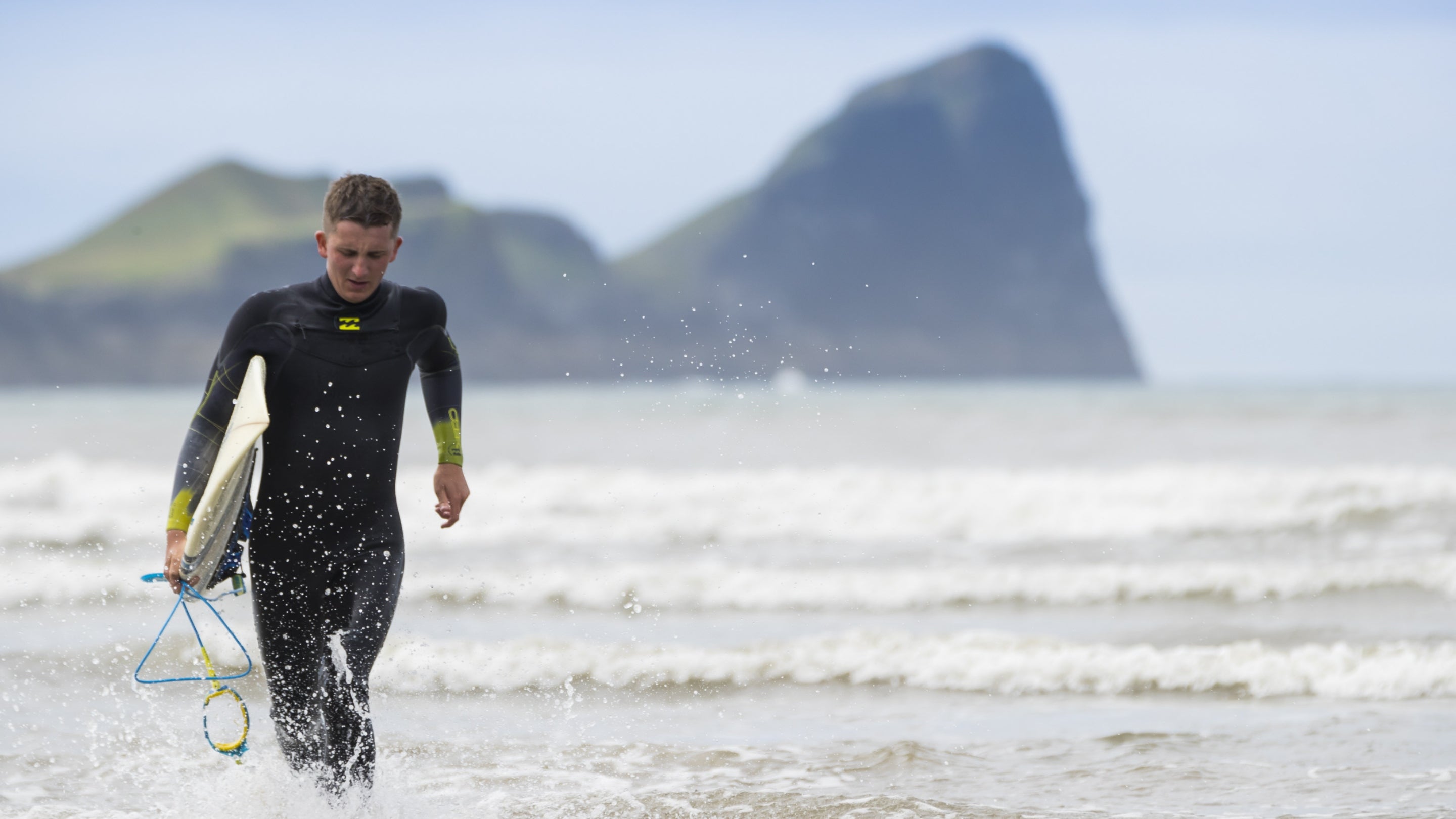 Surfer carrying a board on Rhossili beach, Gower Peninsula, Wales