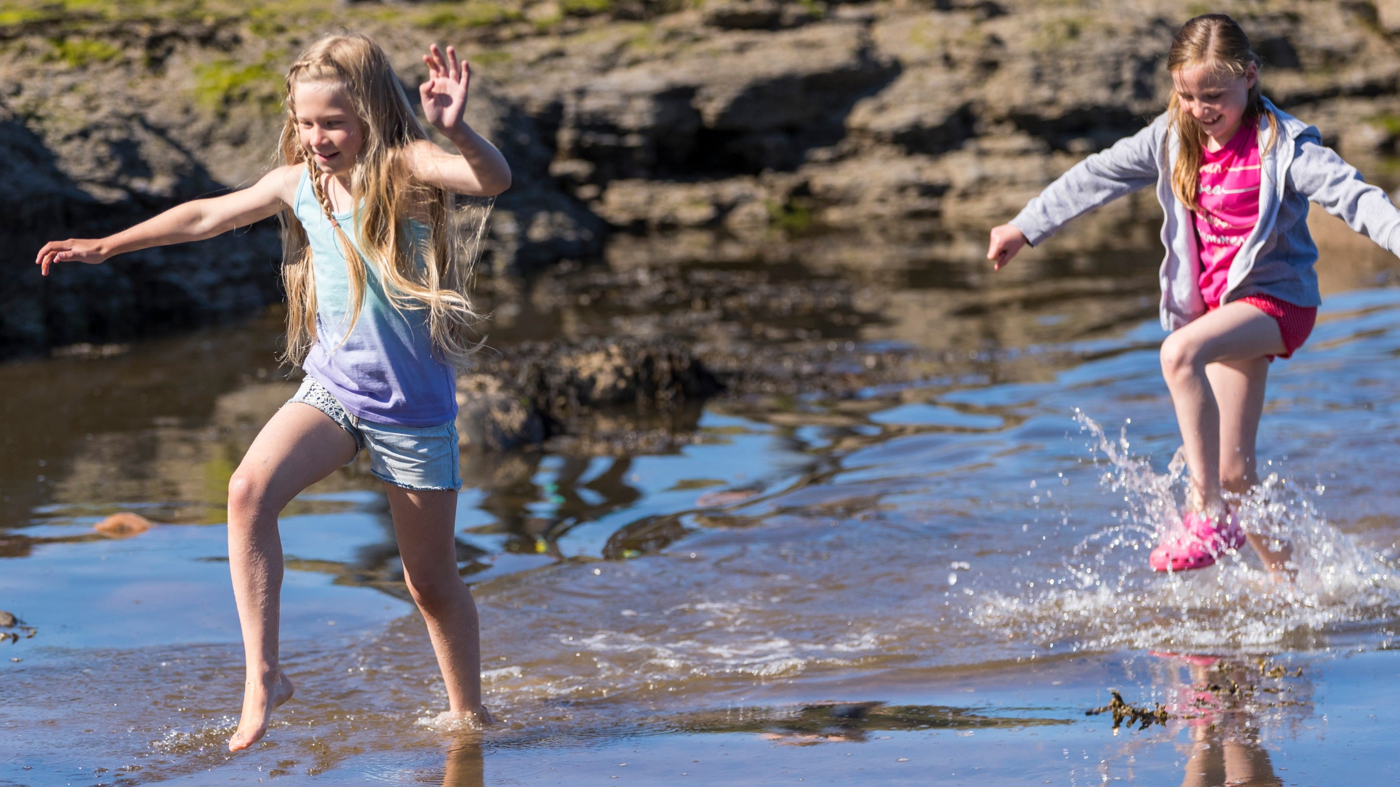 Girls paddling in a stream on the beach at Robin Hood's Bay, North Yorkshire