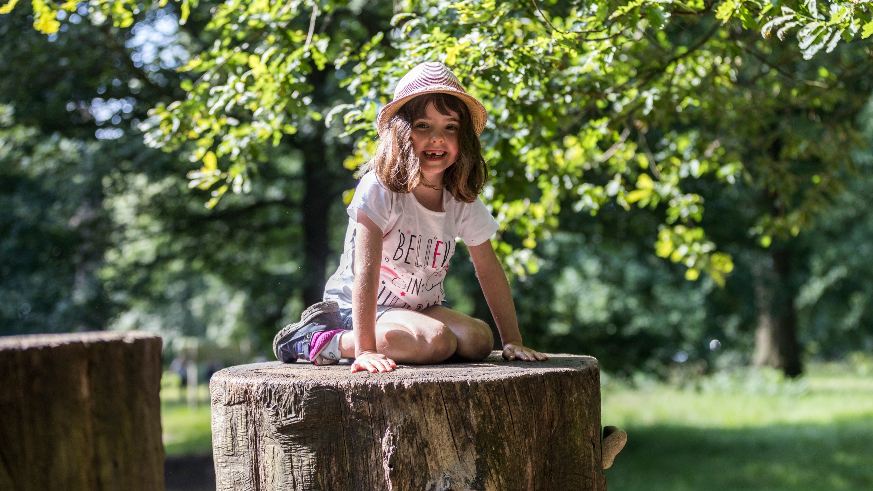 Girl sat on a log in the Log Pile play area at Dunham Massey, Cheshire