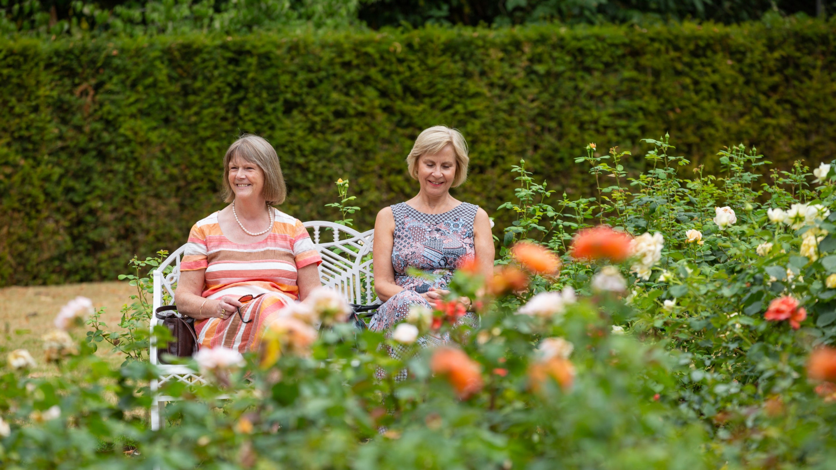 Visitors sat on a bench in the Rose Garden in July at Cliveden, Buckinghamshire