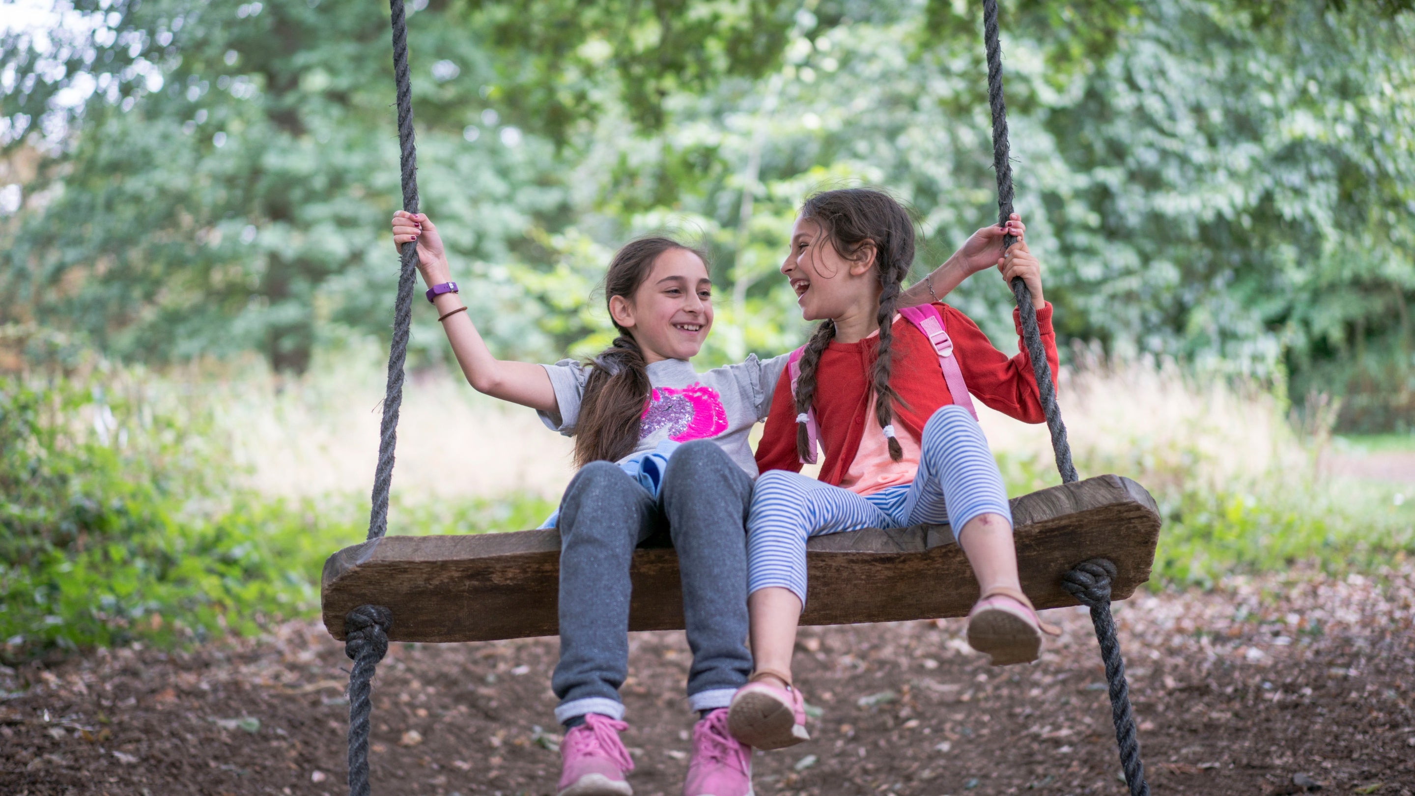 Two children play on one swing in the garden at Osterley Park and House, London