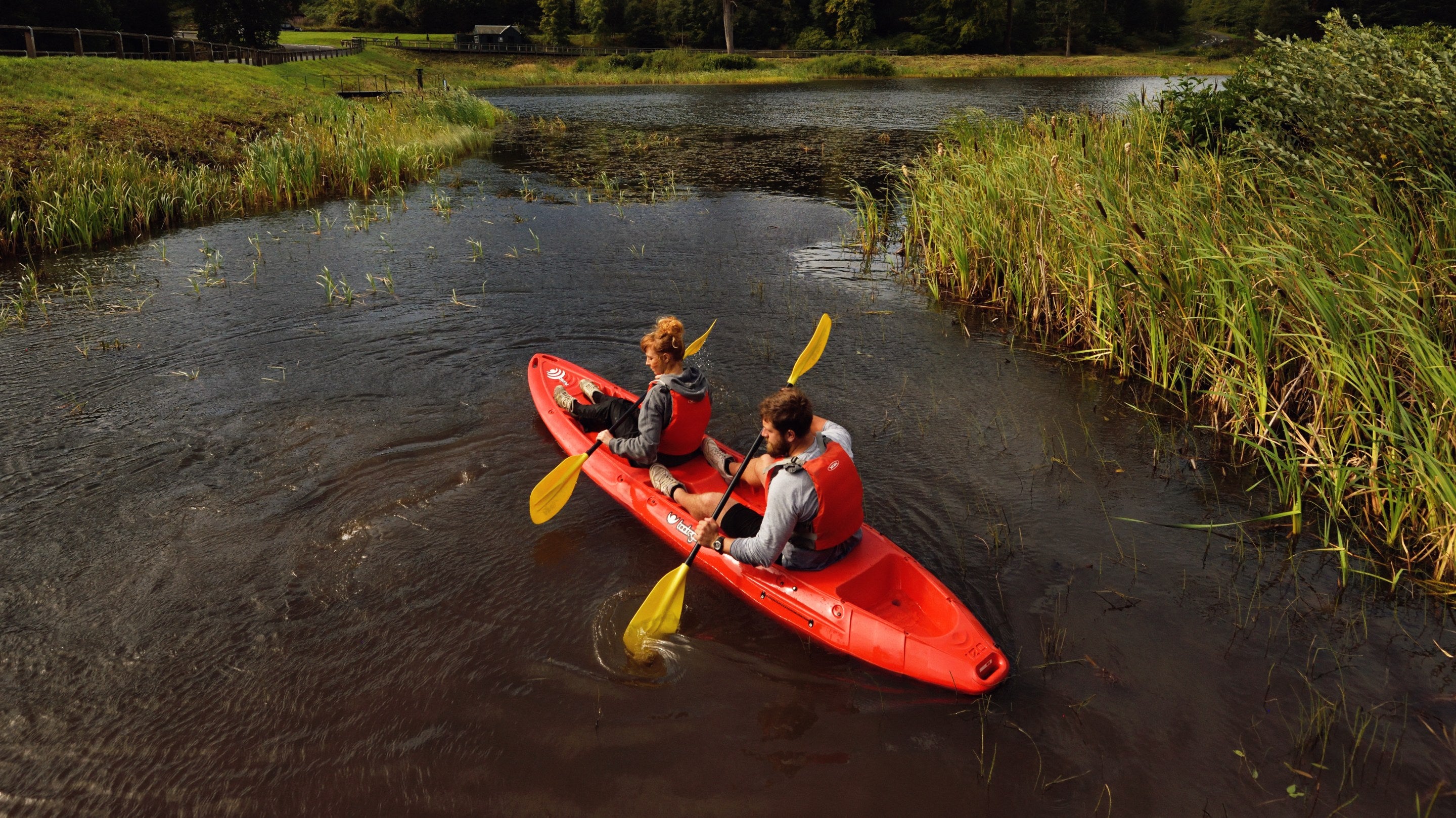 Two visitors in a kayak exploring Tumbleton Lake at Cragside, Northumberland