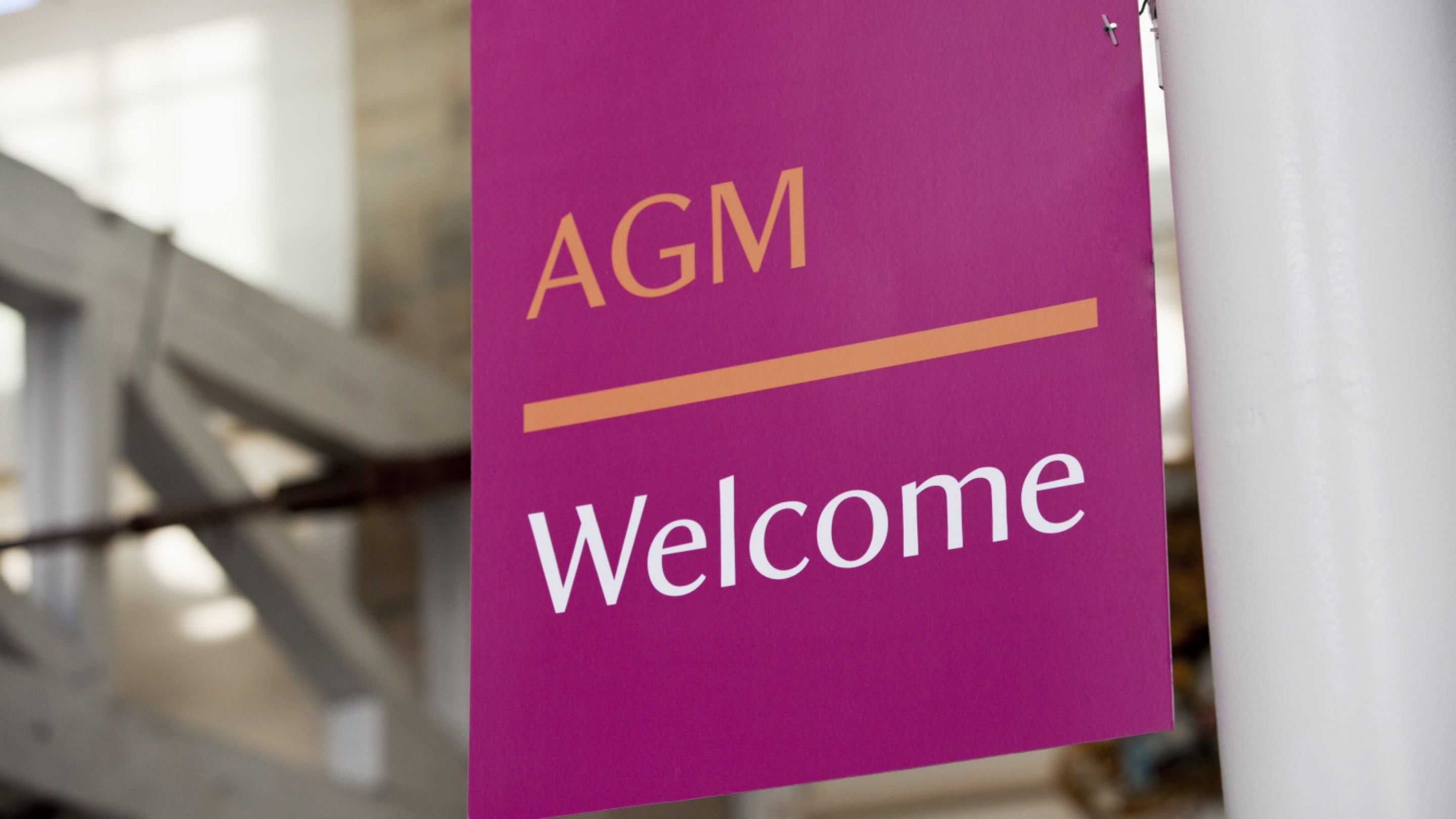 A close-up image of a purple welcome banner at the National Trust's Annual General Meeting, reading 'AGM welcome'.