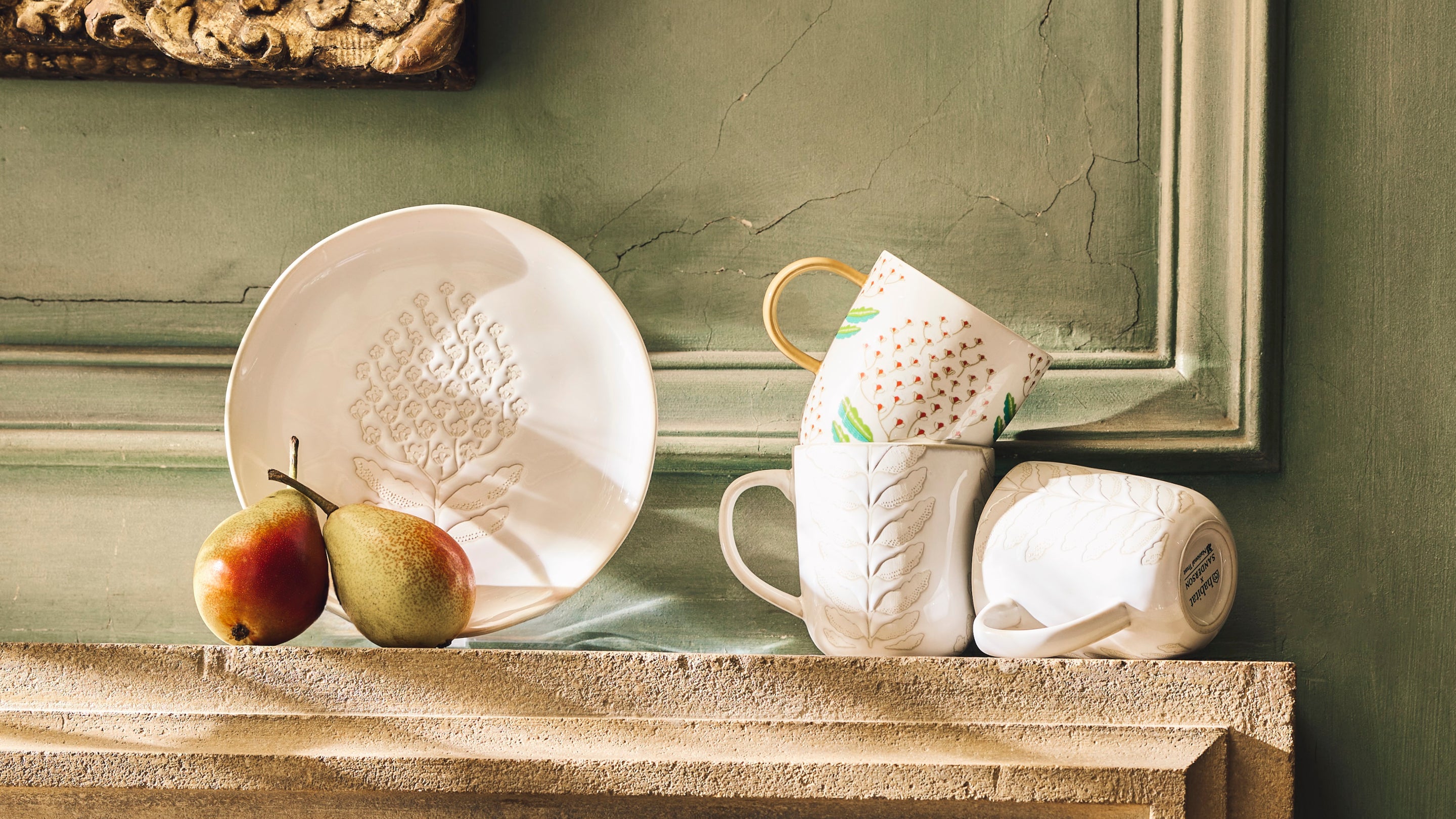 A set of crockery and fruit laid out on a fireplace in the sunshine
