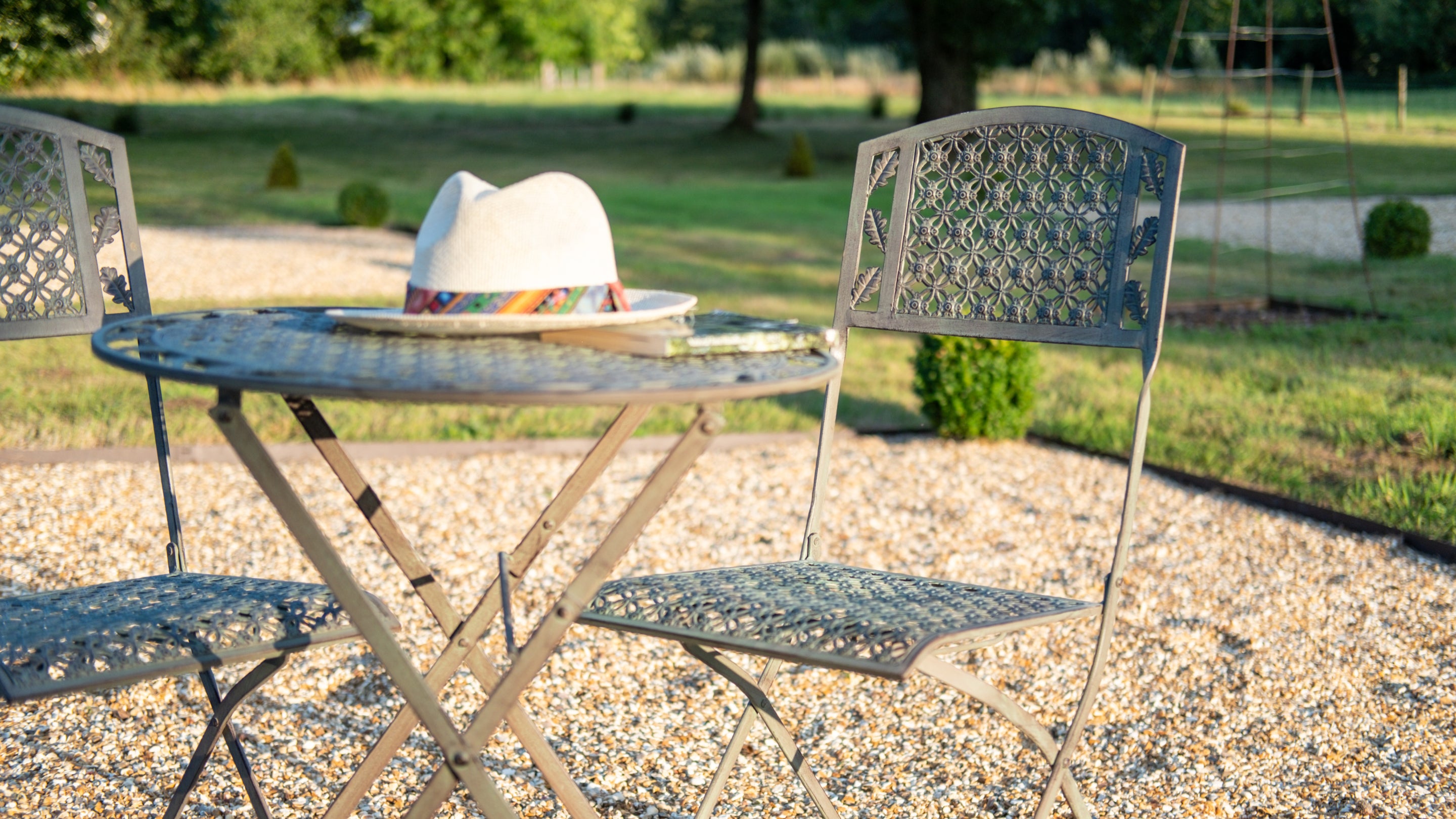 Outdoor furniture, including table and chairs with a hat placed on the table