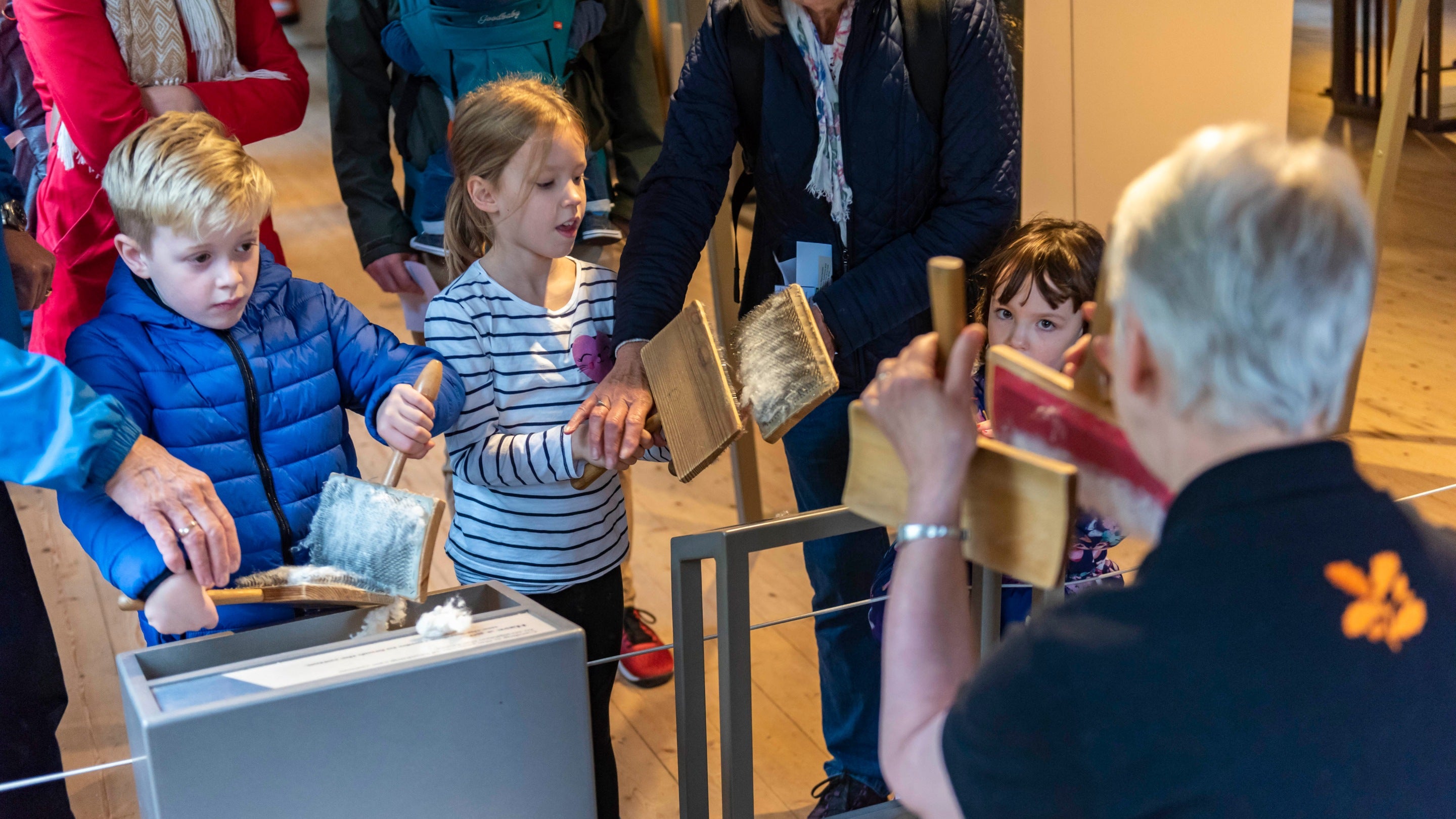A group of visitors and a member of National Trust volunteering team showing the visitors some objects.