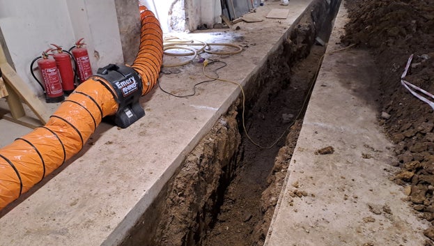 A deep trench through the concrete and soil below. Soil can be seen piled up beside the trench.