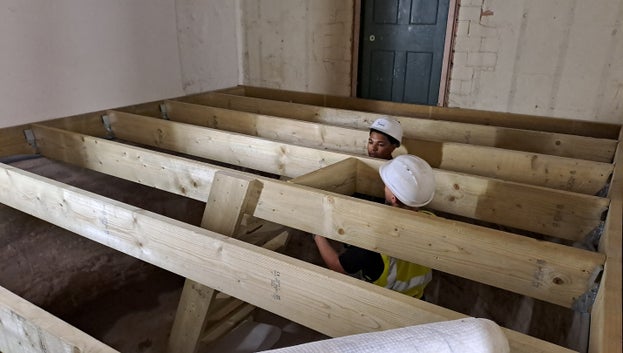Two people can be seen stood in the Cold Bath with wooden beams laid from one side to the other.