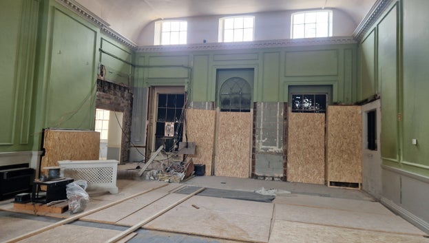 A view of the windows that are covered in black paint, with wooden boards led over some of them.