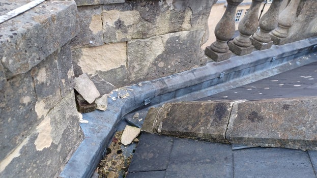 On the roof there is an element of masonry that has crumbled and broken off laying in the gutters.