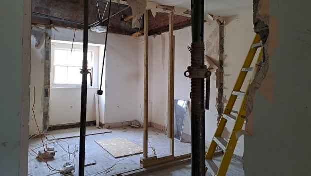 A picture of a room that shows props and wooden planks where a partition wall once was.