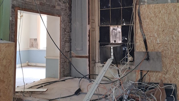 You can see an opening in a wall, boarded up floor and a mass of cables that were once the old lift workings.