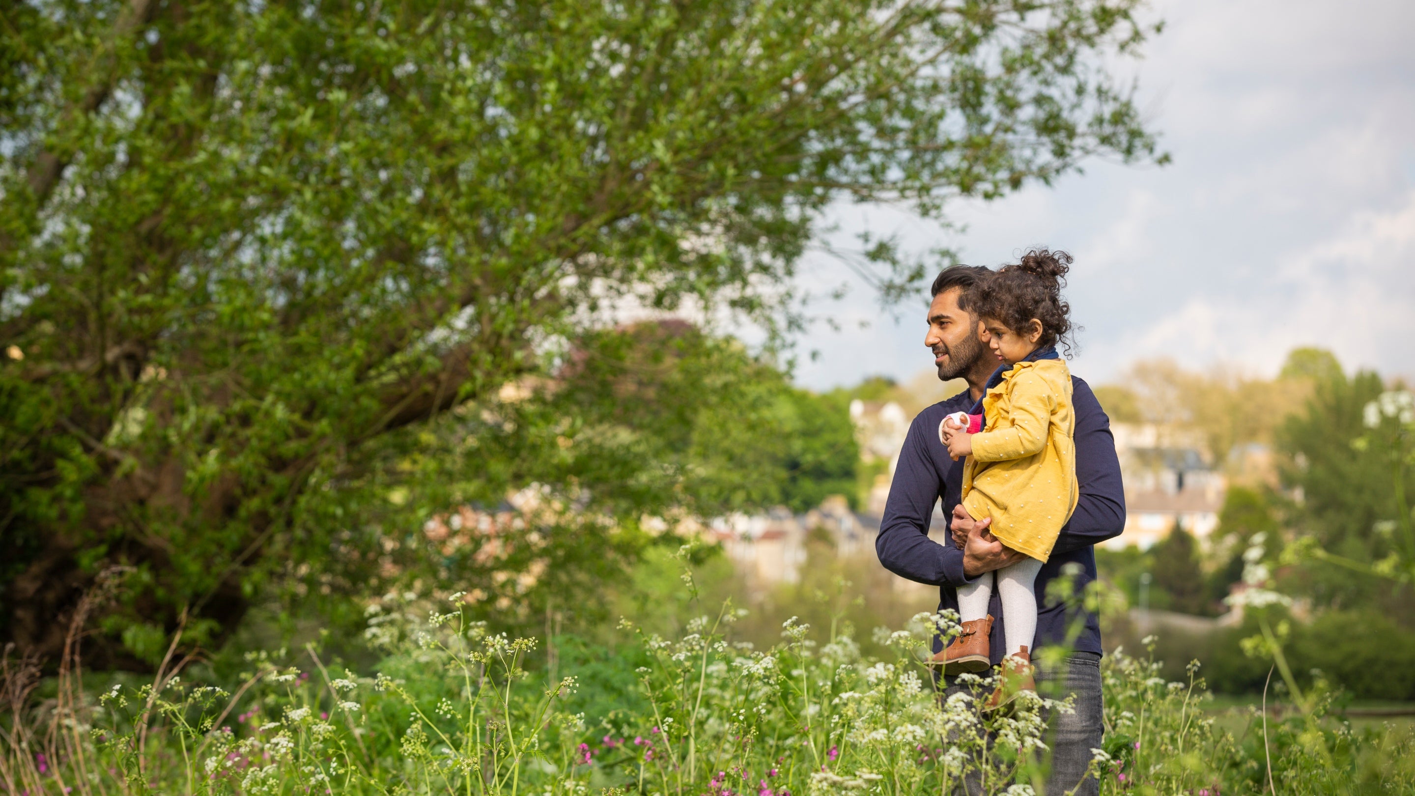 An adult and child looking at wildflowers in Bathampton Meadows