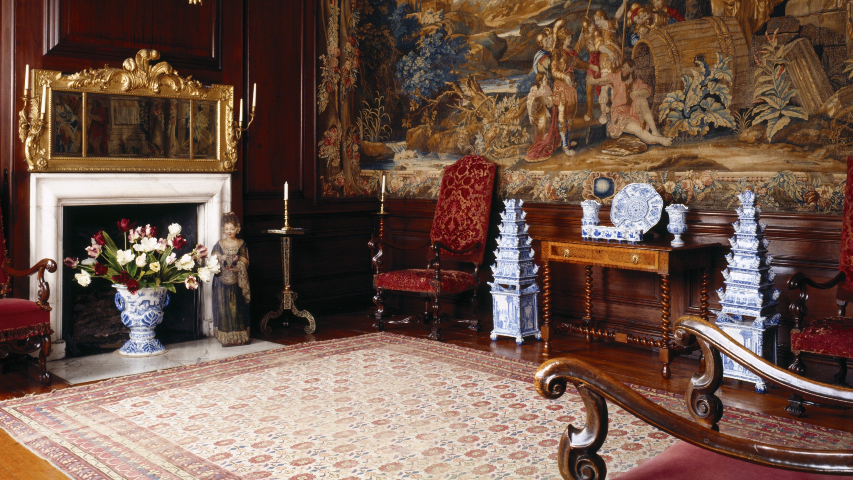 The interior of the Diogenes Room at Dyrham Park, Bath, showing rich tapestries and Delftware, including two flower pyramid vases.