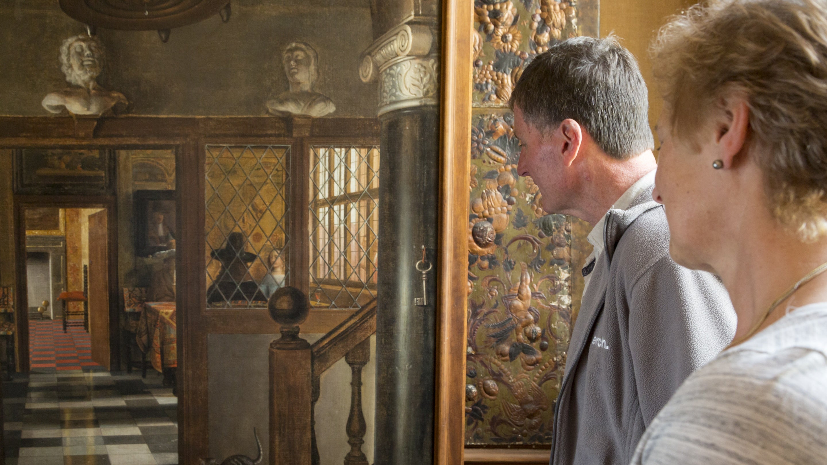 Visitors looking at a trompe l-oeil painting by Samuel van Hoogstraten at Dyrham Park, depicting a realistic view through a doorway