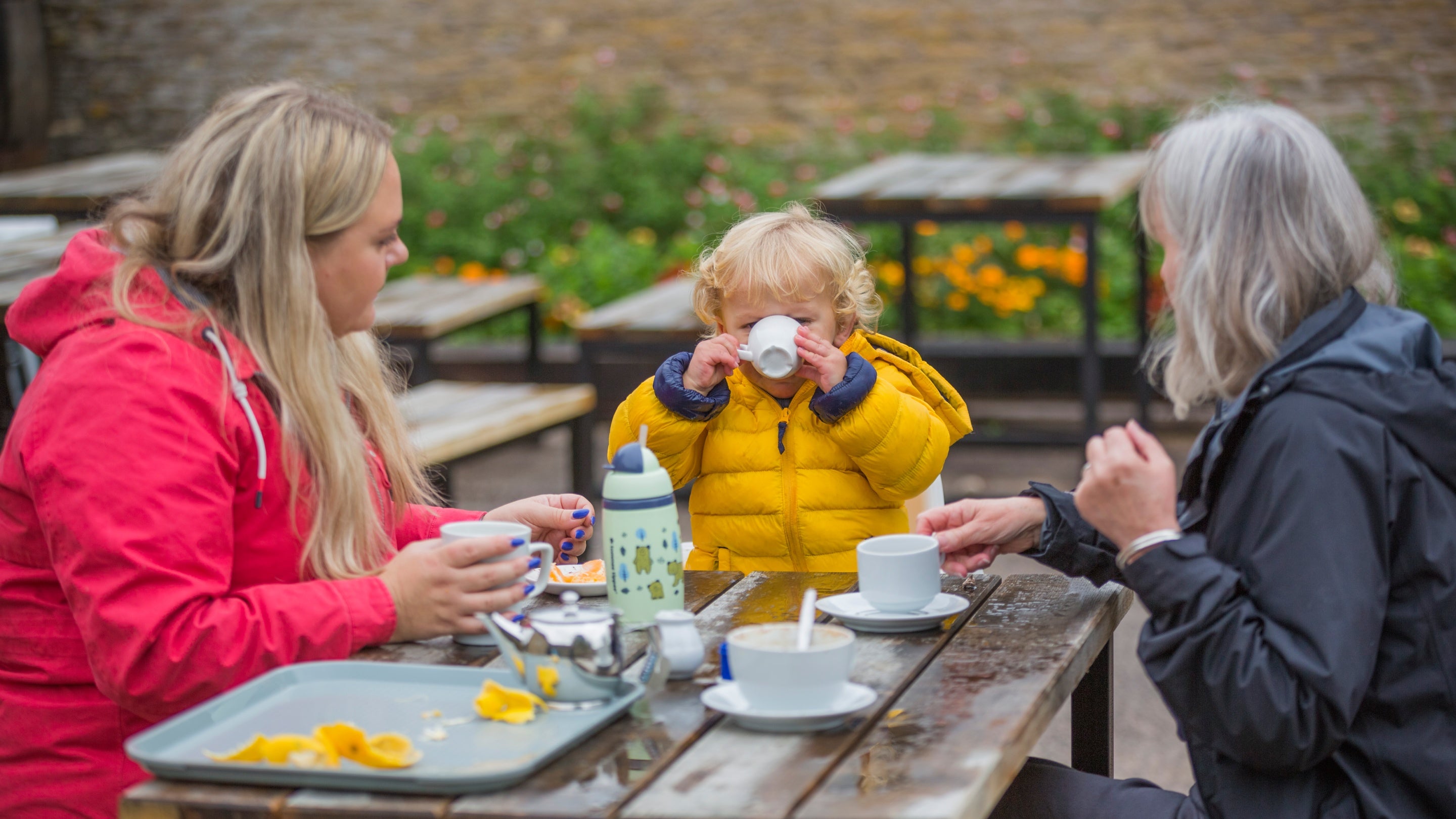 A family in the outdoor seating area of the café at the Old Lodge at Dyrham Park, South Gloucestershire