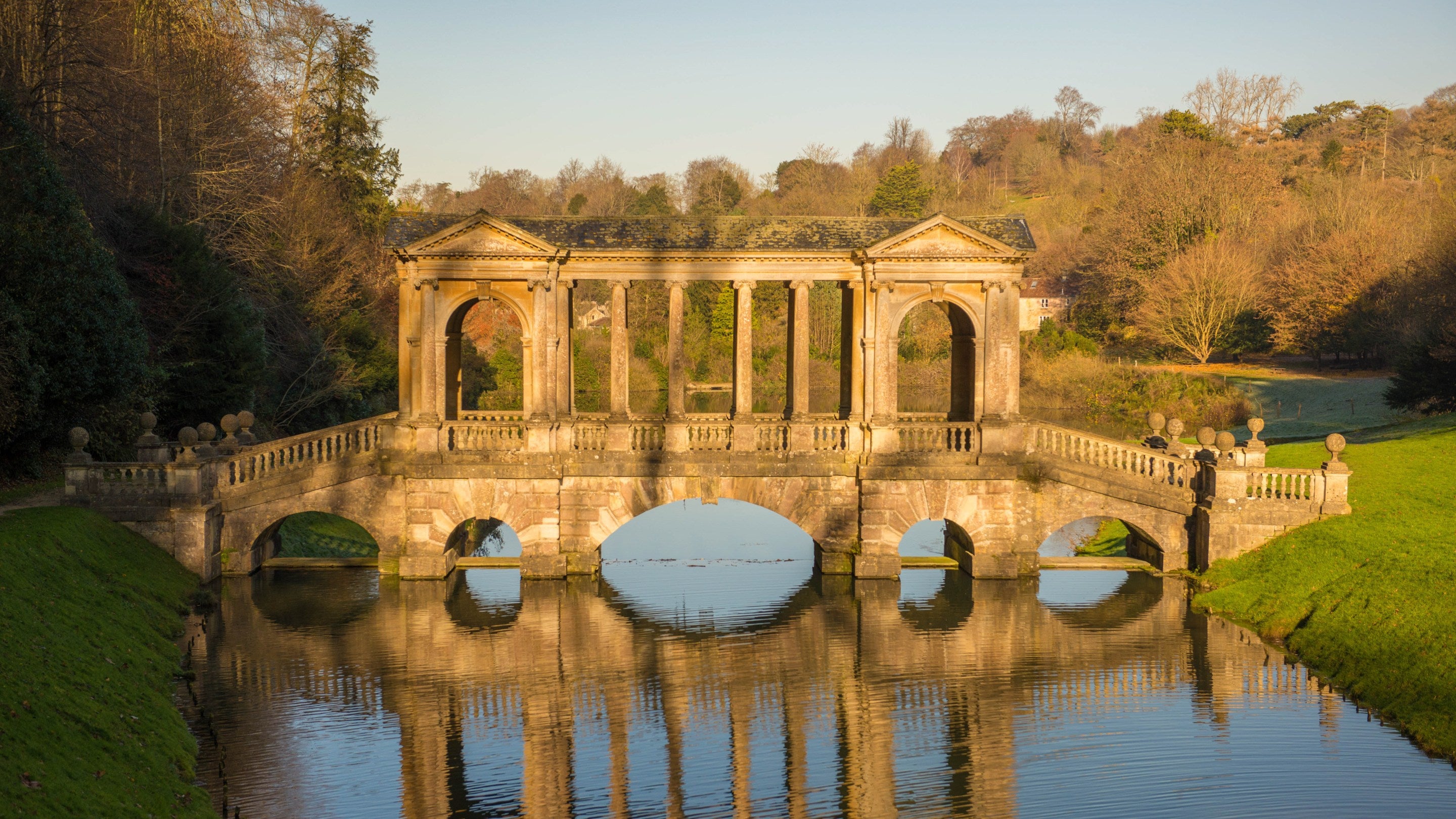 The Palladian Bridge in Bath in sunshine over the lake at Prior Park in December