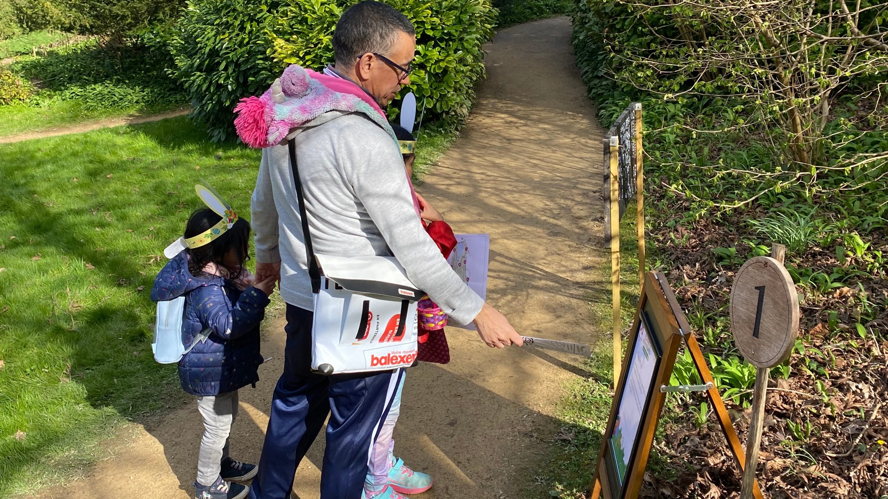 A family exploring one of the Easter stations on the trail, wearing bunny ears and carrying trail sheets.