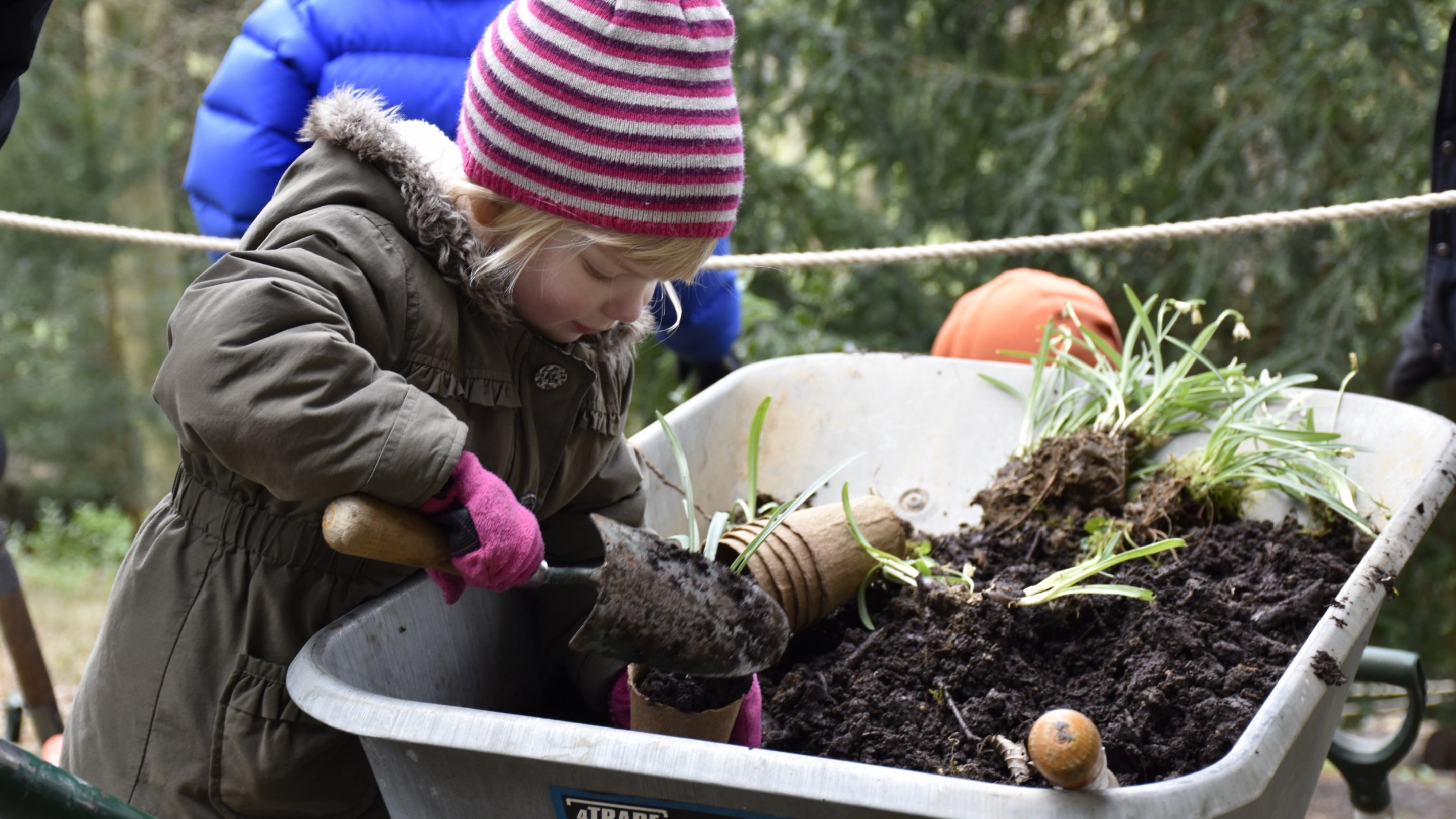 A girl pots a plant in compost at Prior Park in Bath, Somerset