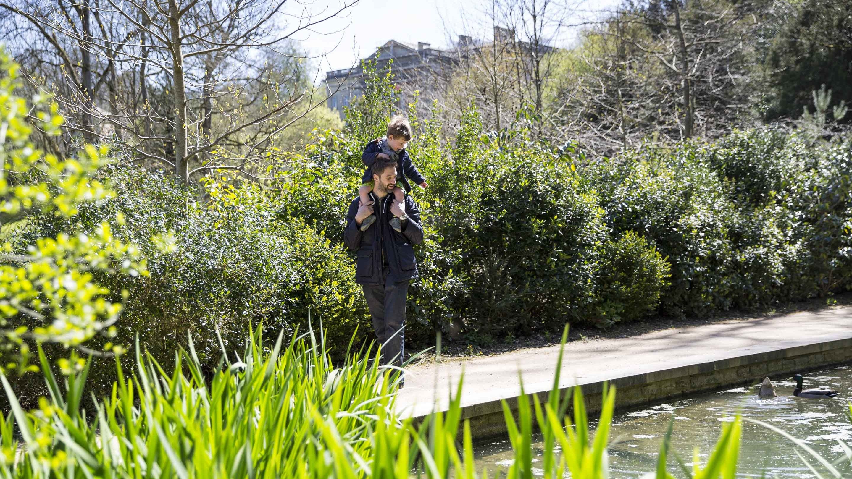 Man carrying little boy on his shoulders at Prior Park, Somerset