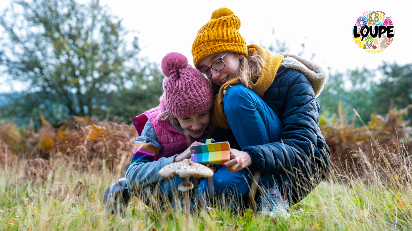 Two young people take a photo of a mushroom on a mobile phone