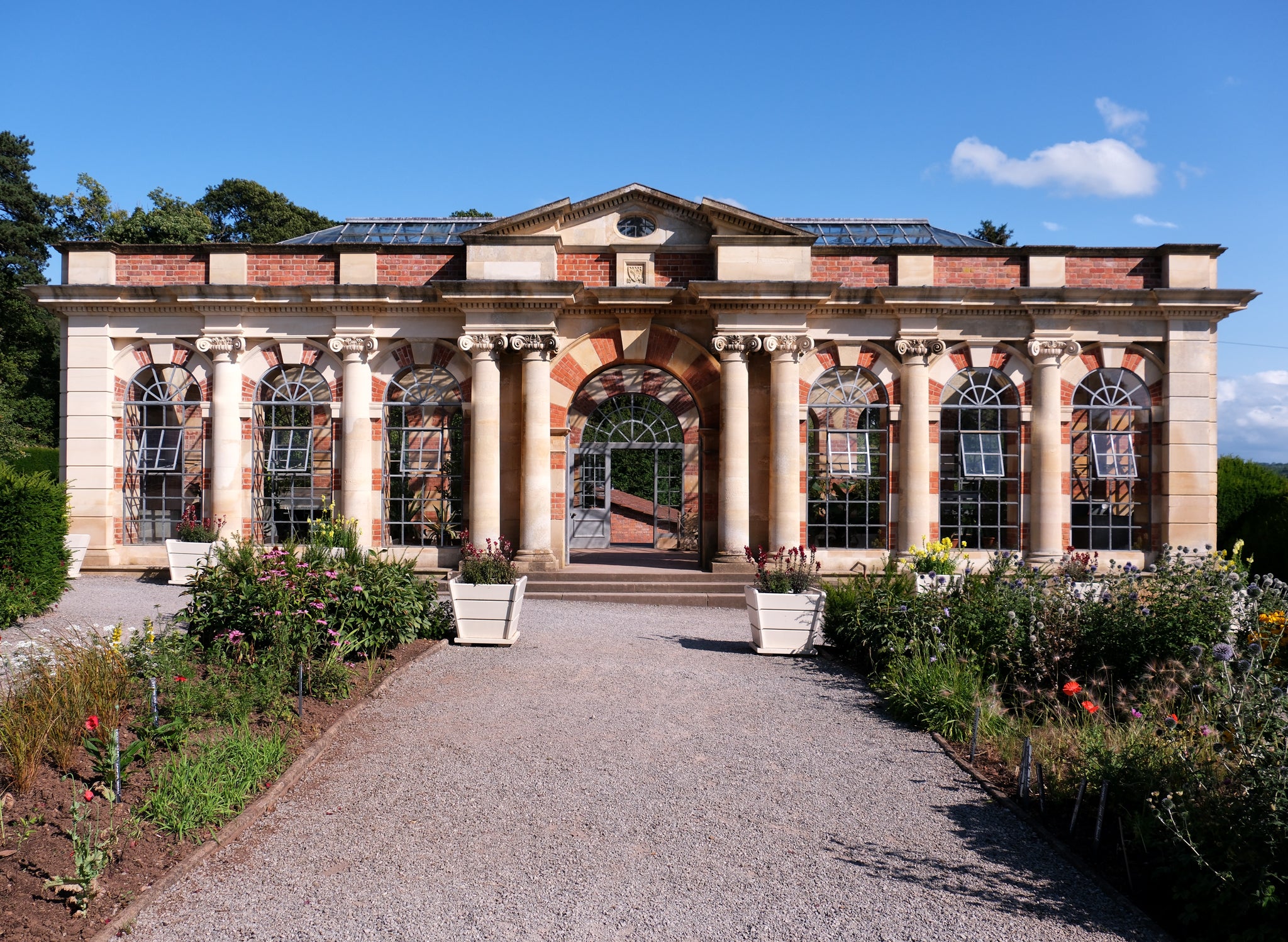 Tyntesfield's Orangery during summer, showing rows and pots of flowers.