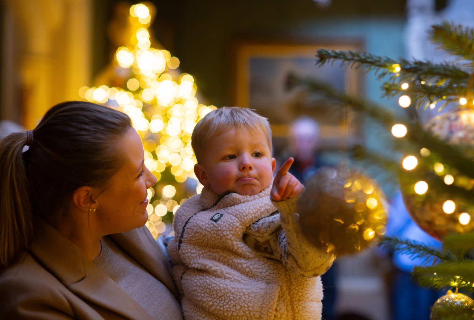 A mother and child enjoying a Christmas tree in the Hall of Tyntesfield House, Somerset