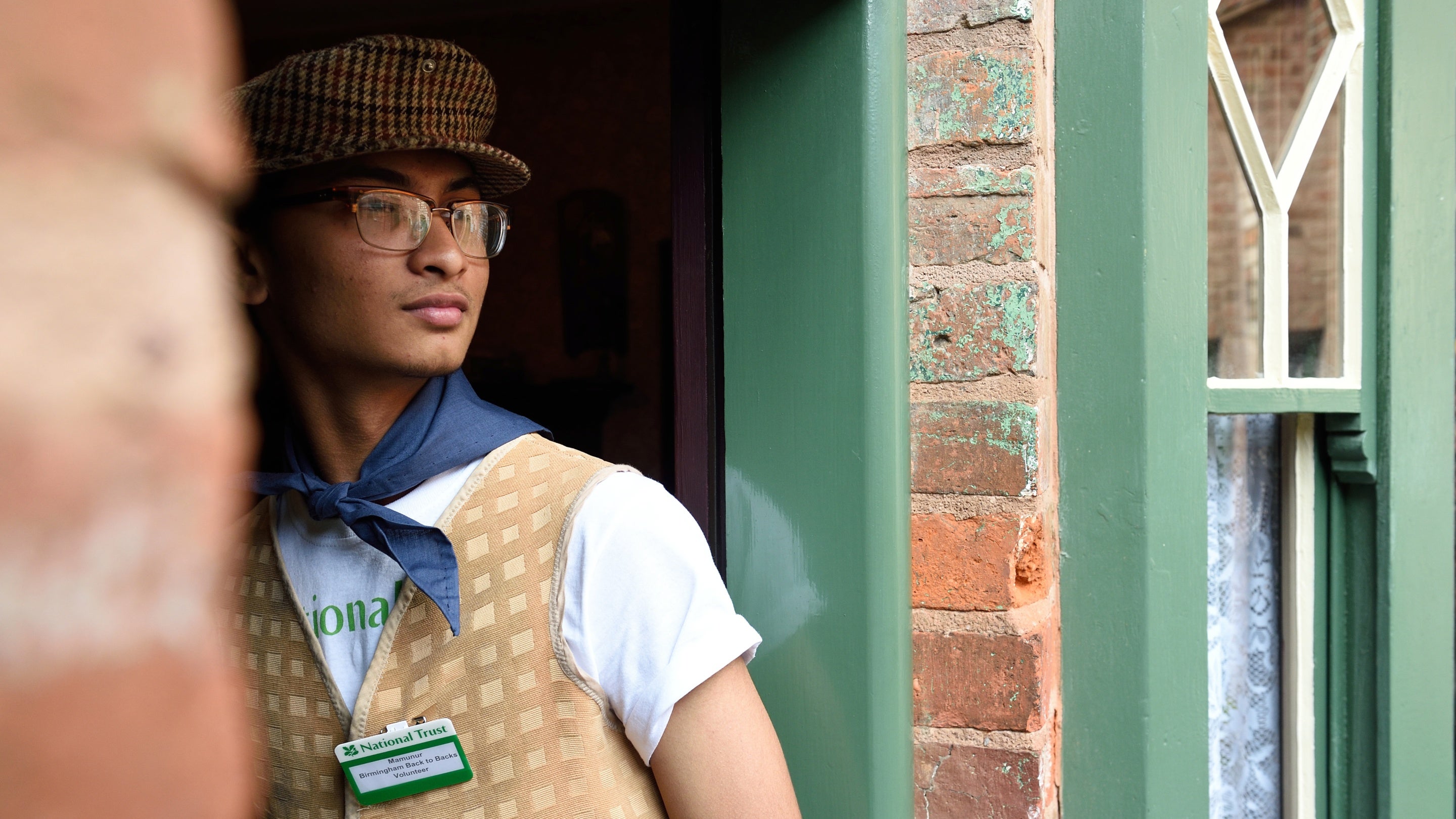 A young volunteer in costume stands in the doorway of one of the Birmingham back to backs, West Midlands.