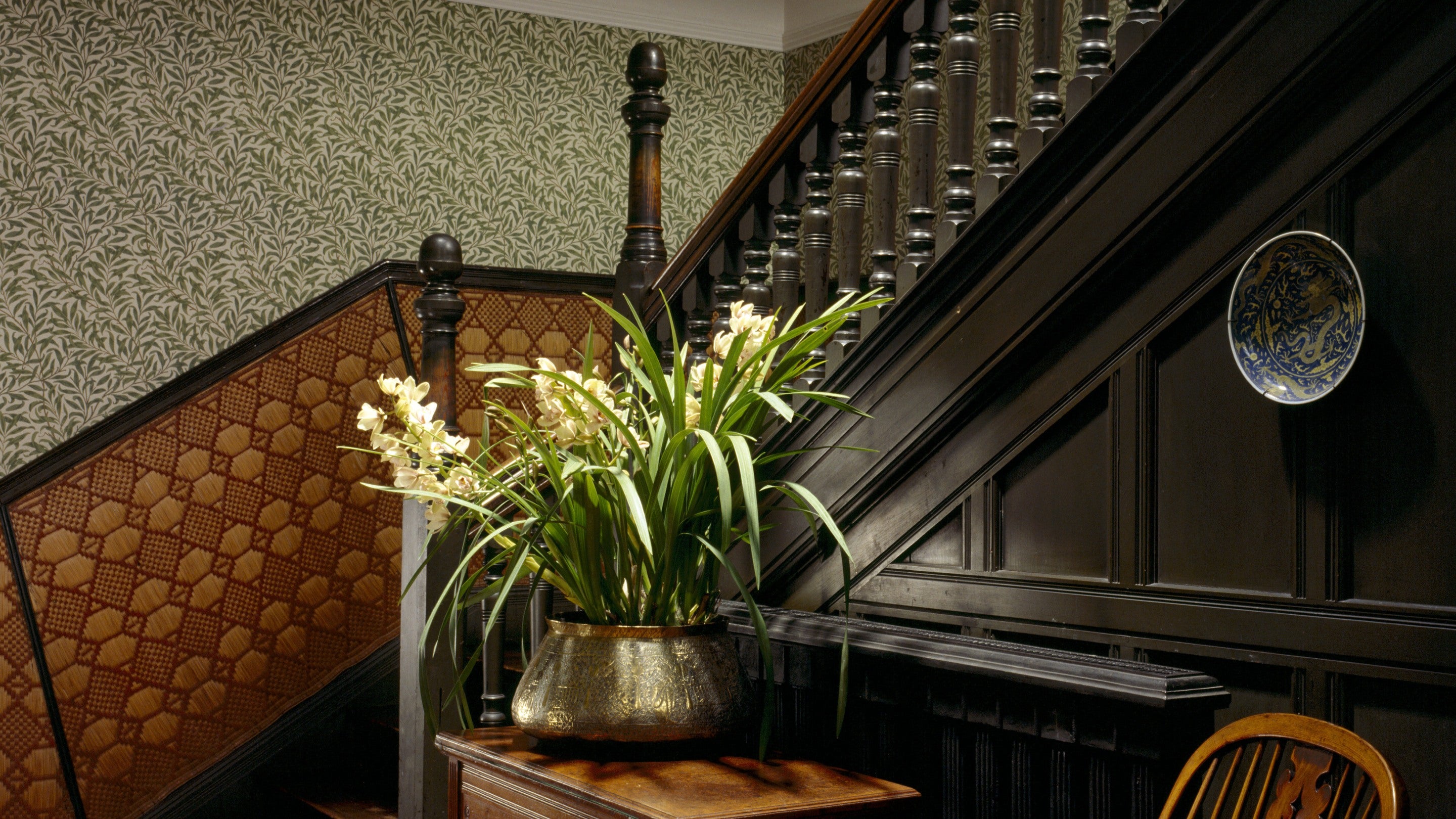The visitor staircase at Wightwick Manor, West Midlands, featuring Indian rush-work below the dado rail and William Morris' Willow Bough pattern wallpaper above