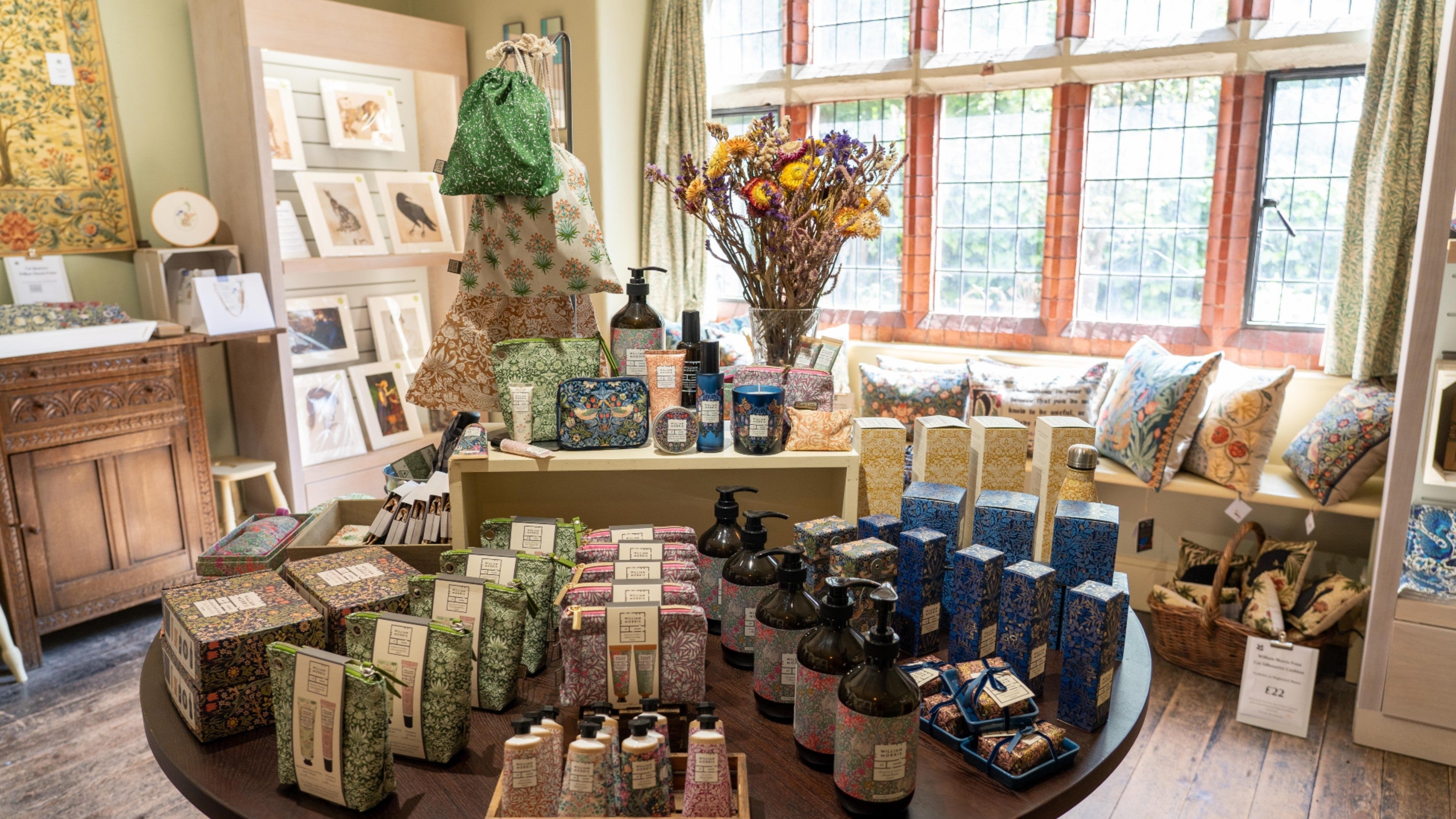 A view of the main sales table in the Morris Shop room in the Old Manor, showing a range of items decorated with Morris and Co patterns,