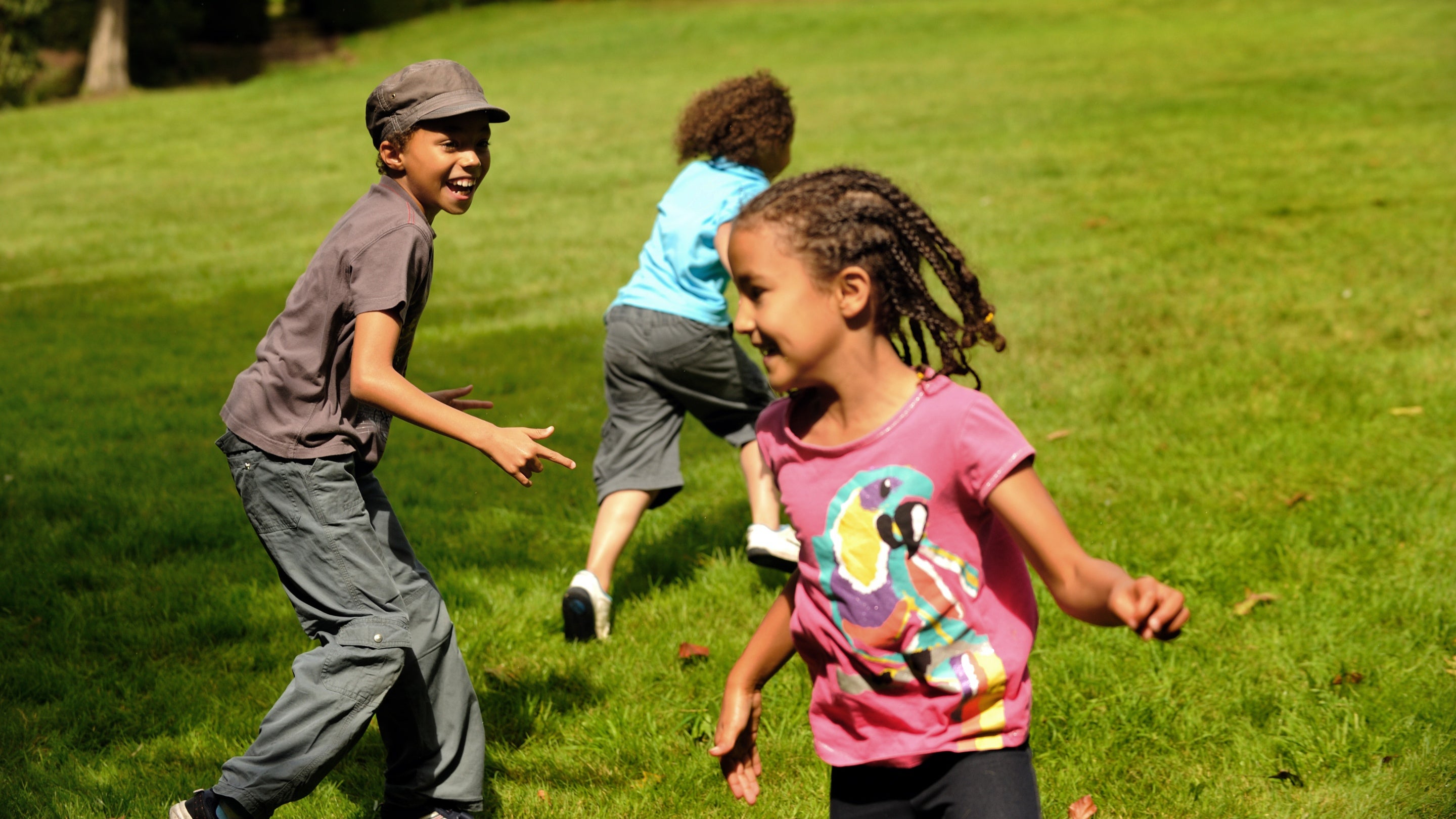 Three children running and playing on the grass