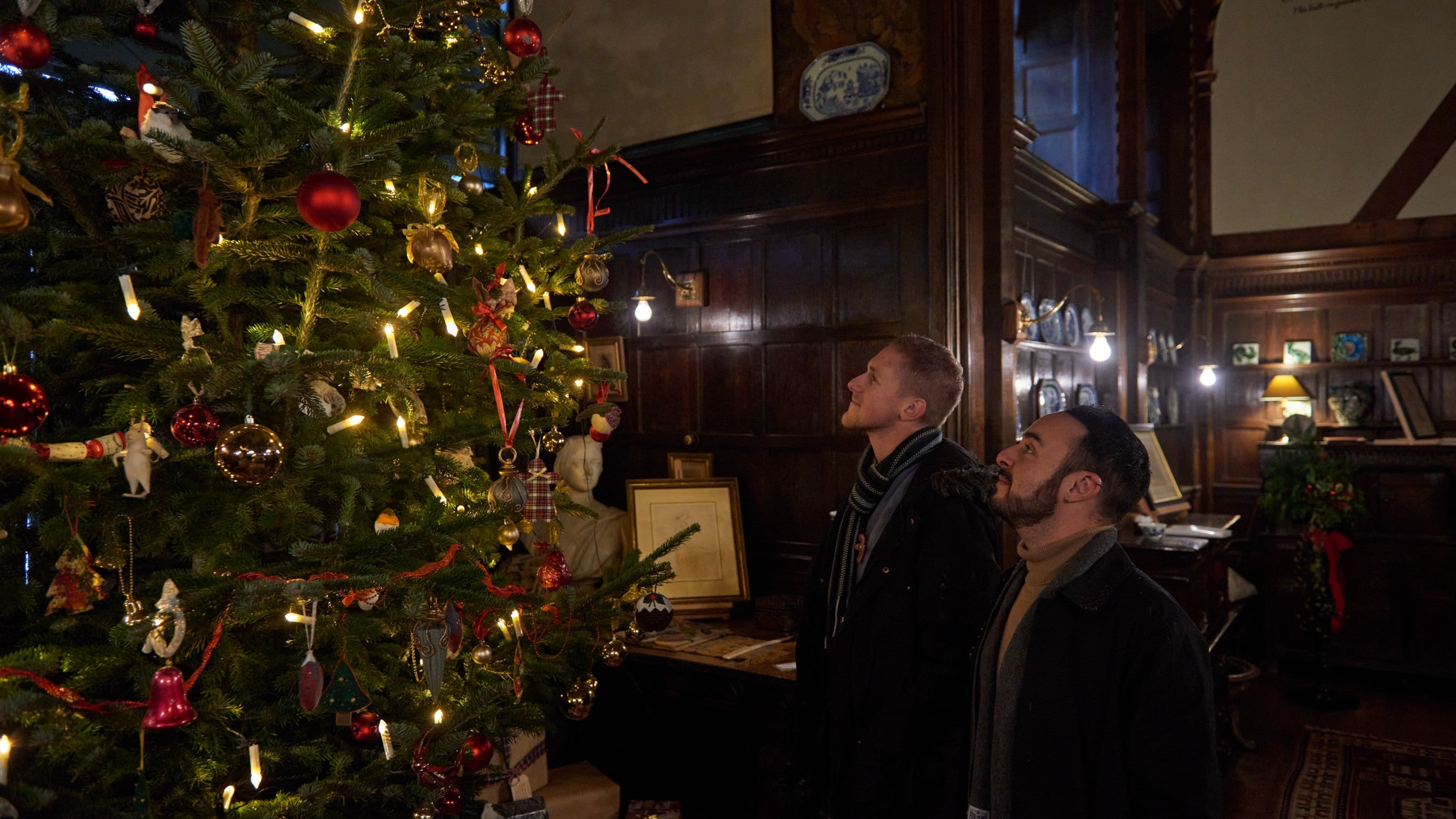 Two visitors look up at the decorated Christmas tree in the Great Parlour at Wightwick Manor