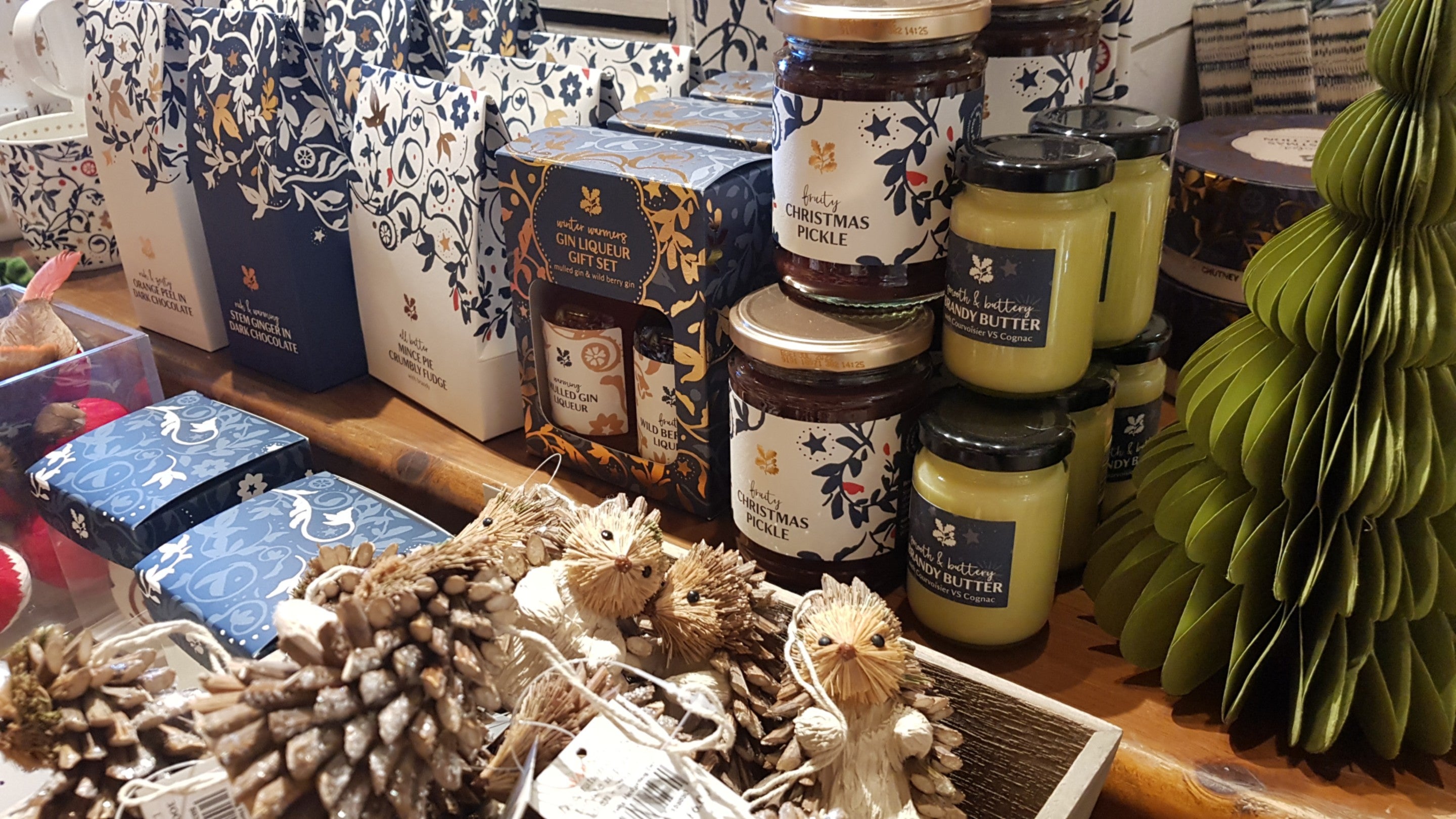 A close up picture of a display table in the shop at Wightwick, with a range of Christmas decorations and food, such as brandy butter and pickles.