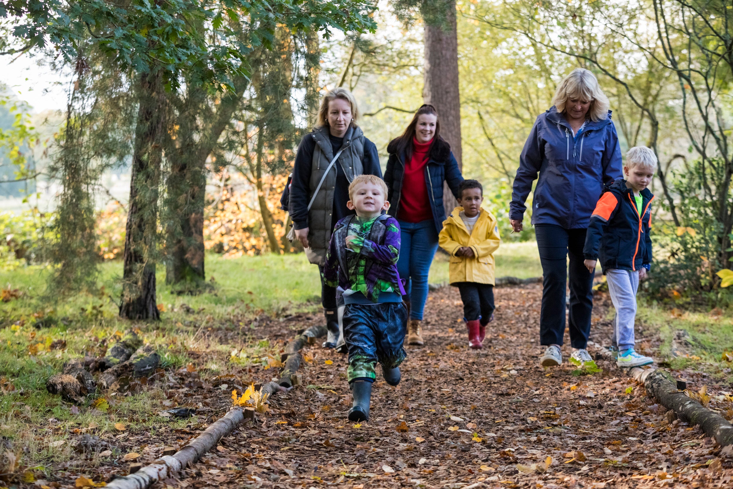Parents and children walking along an autumnal path in the woods